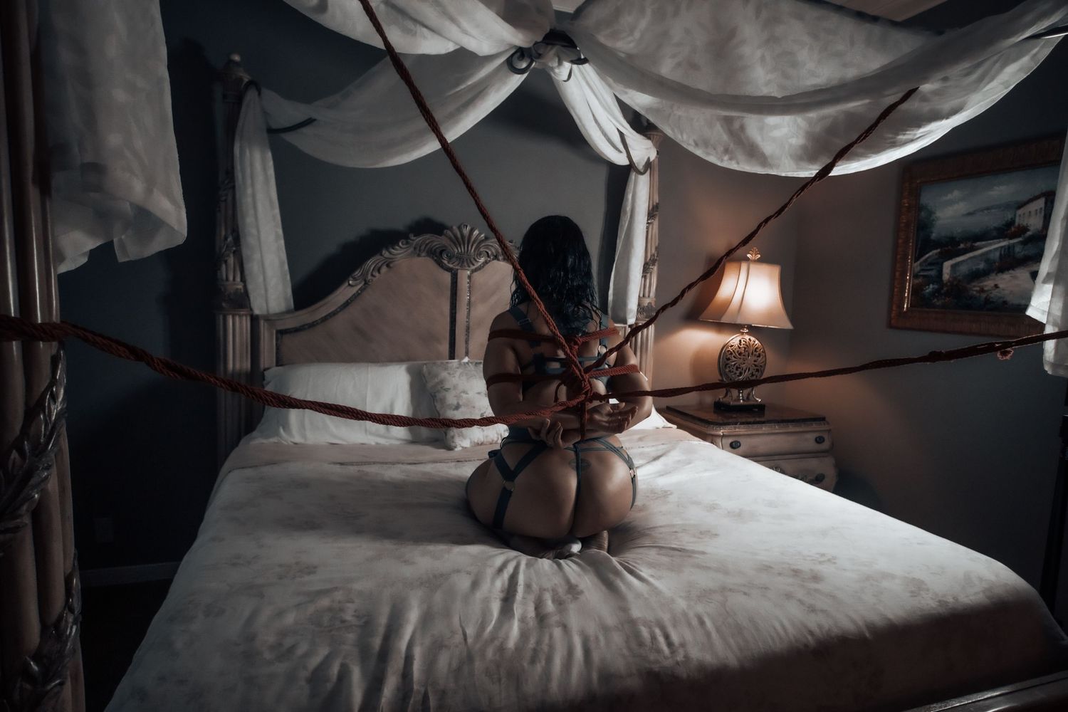 Moody shibari portrait in a bedroom setting, capturing trust, vulnerability, and artistic connection through rope and light. boudoir