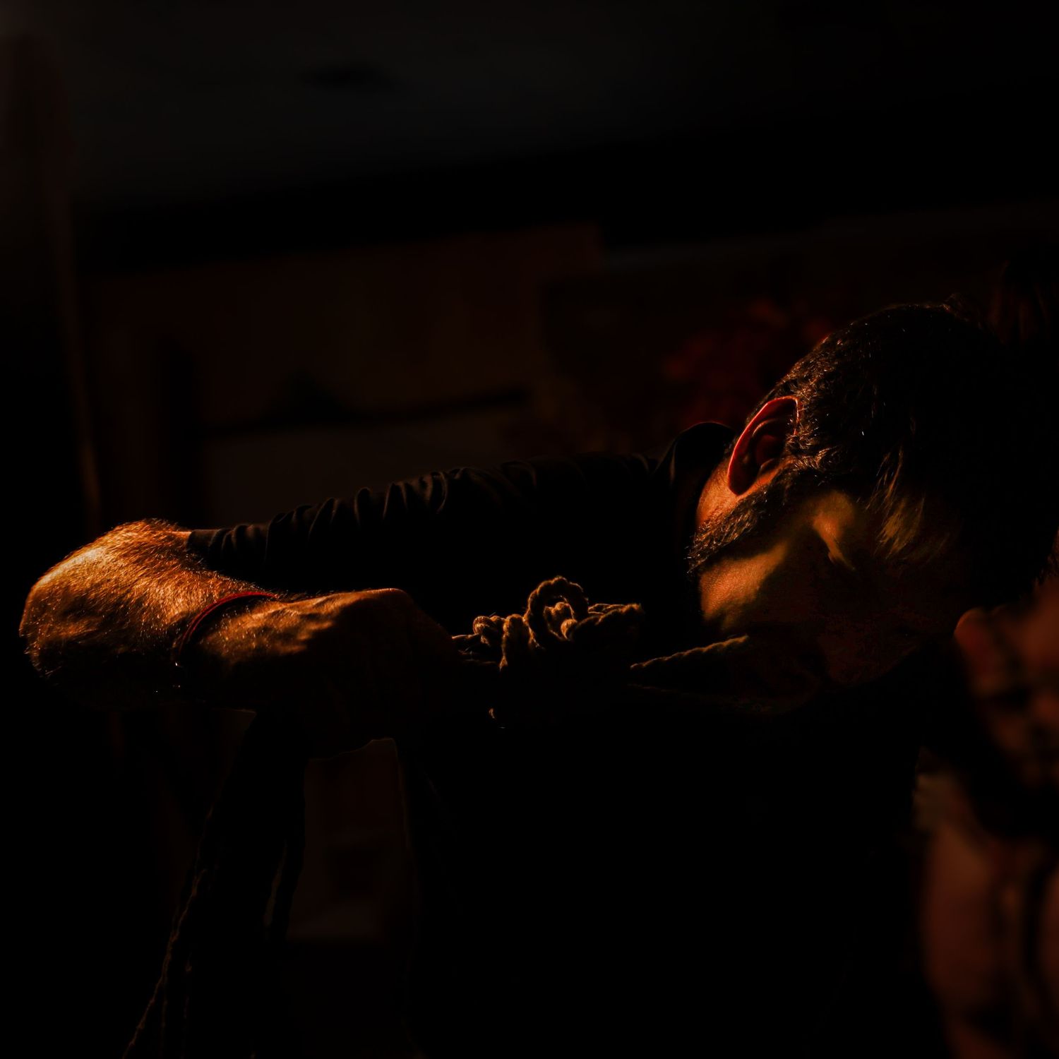 Intimate, low-light portrait showing hands and rope in motion, capturing trust, focus, and the quiet intensity of a shibari-informed artisti