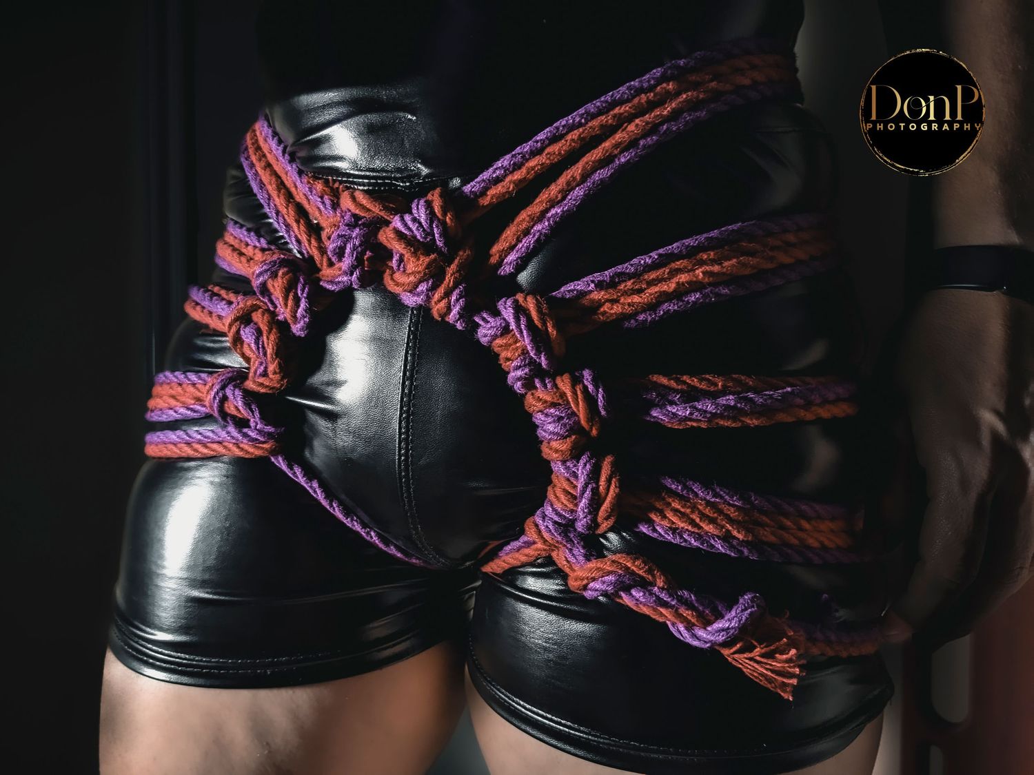 Close-up of shibari rope harness on a leather-clad body, highlighting tension, structure, and craftsmanship boudoir