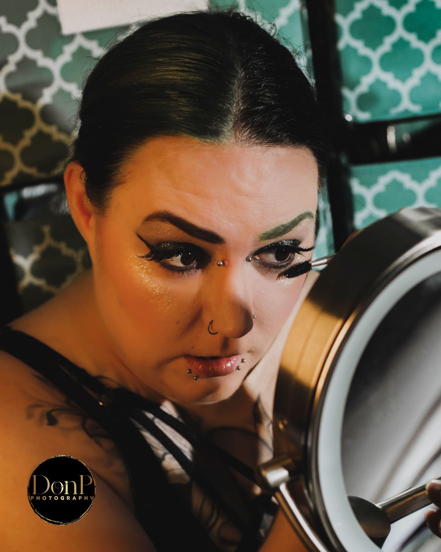 Intimate boudoir photography close-up capturing a getting-ready moment with dramatic makeup, reflection, and focused expression.