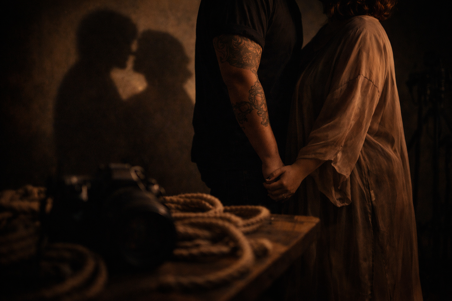 Intimate couple portrait focused on trust and connection, captured in low light with hands held, soft shadows, and a sense of shared presenc