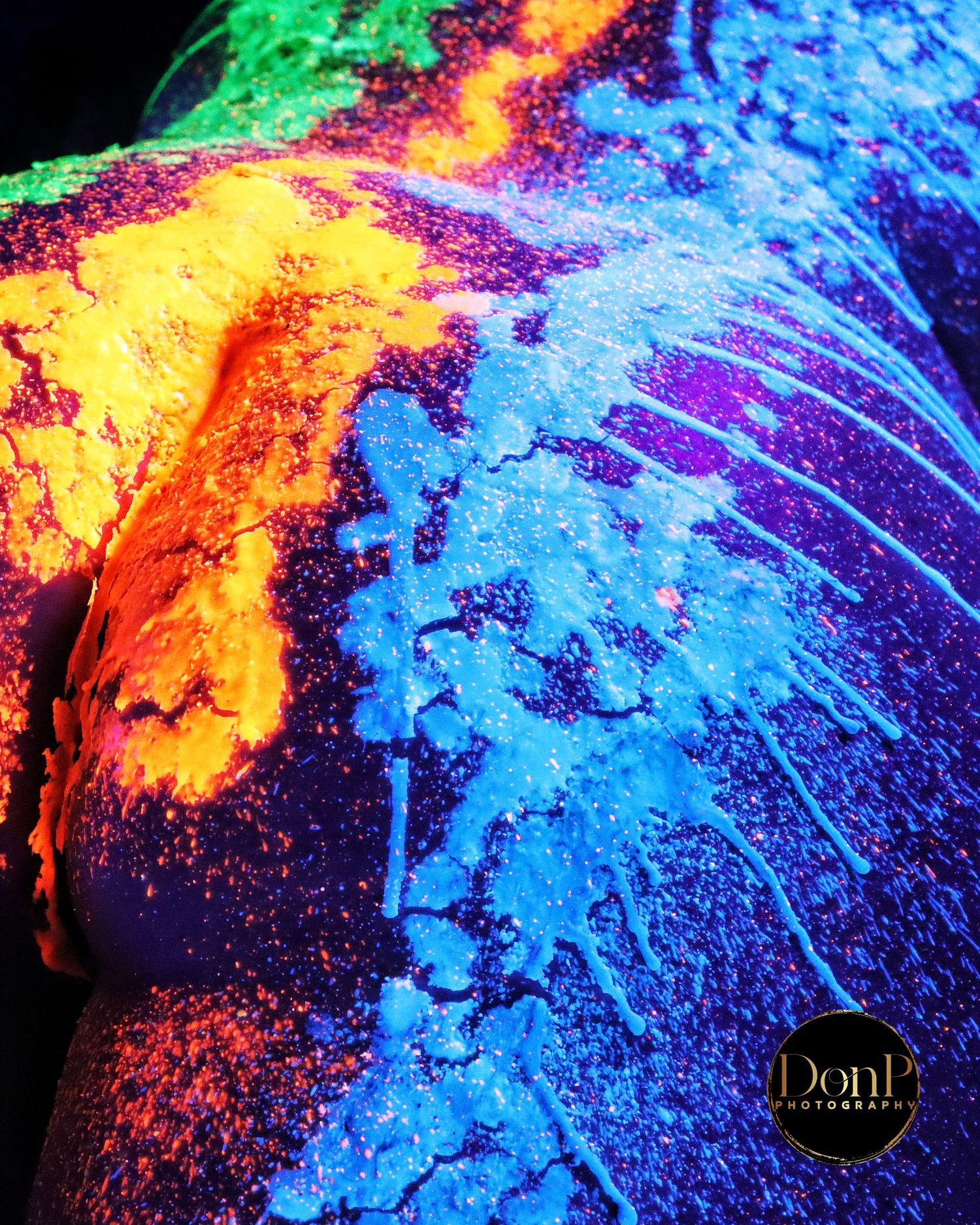 UV body paint portrait transforming skin into living canvas—experimental boudoir photography exploring color, texture, and embodied art.