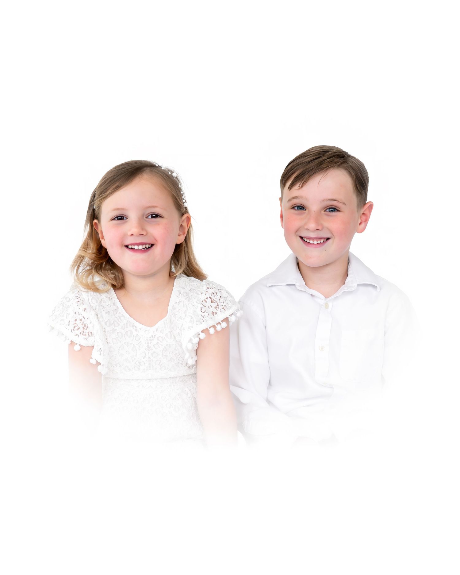 Two smiling children in white outfits posing together for a portrait photo.