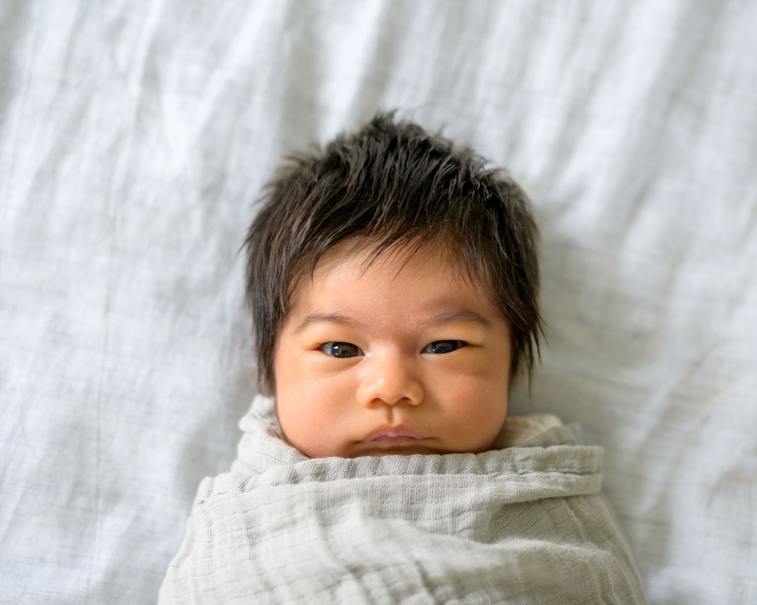 Series of a sleeping newborn baby wrapped in soft gray bedding.
