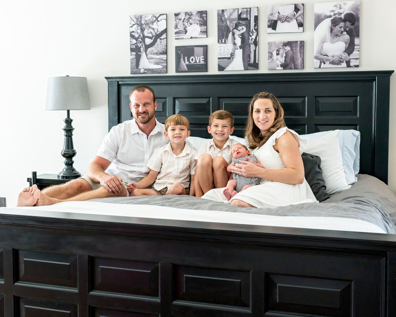 Family lifestyle photography session on large bed with black headboard.