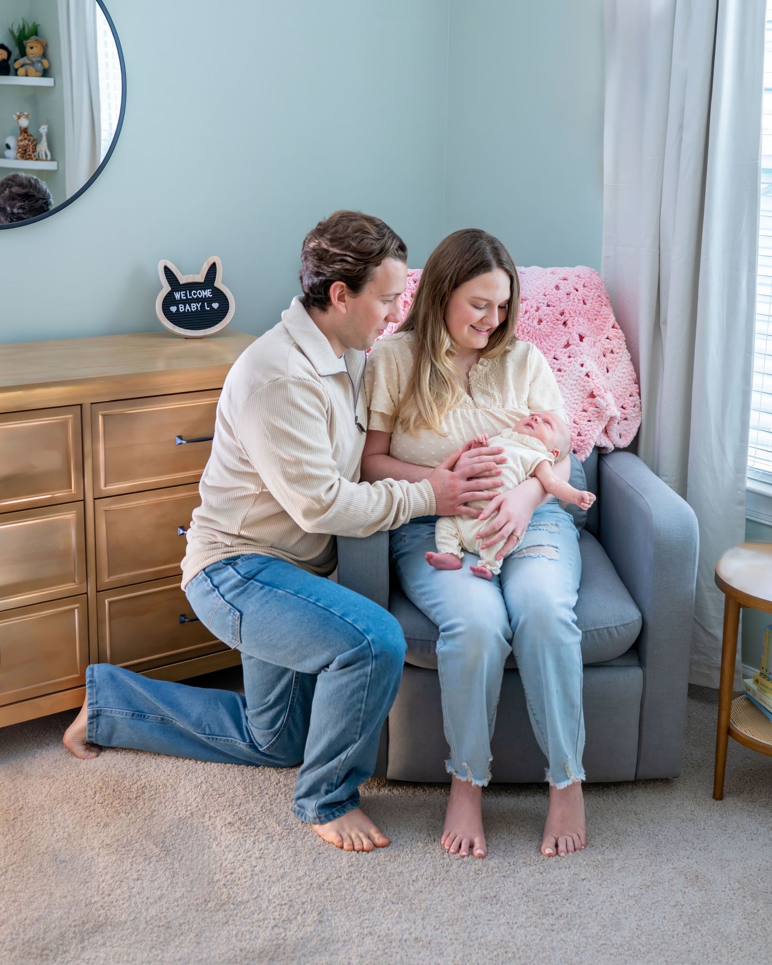 Family sitting together on grey couch in blue room with wainscoting.