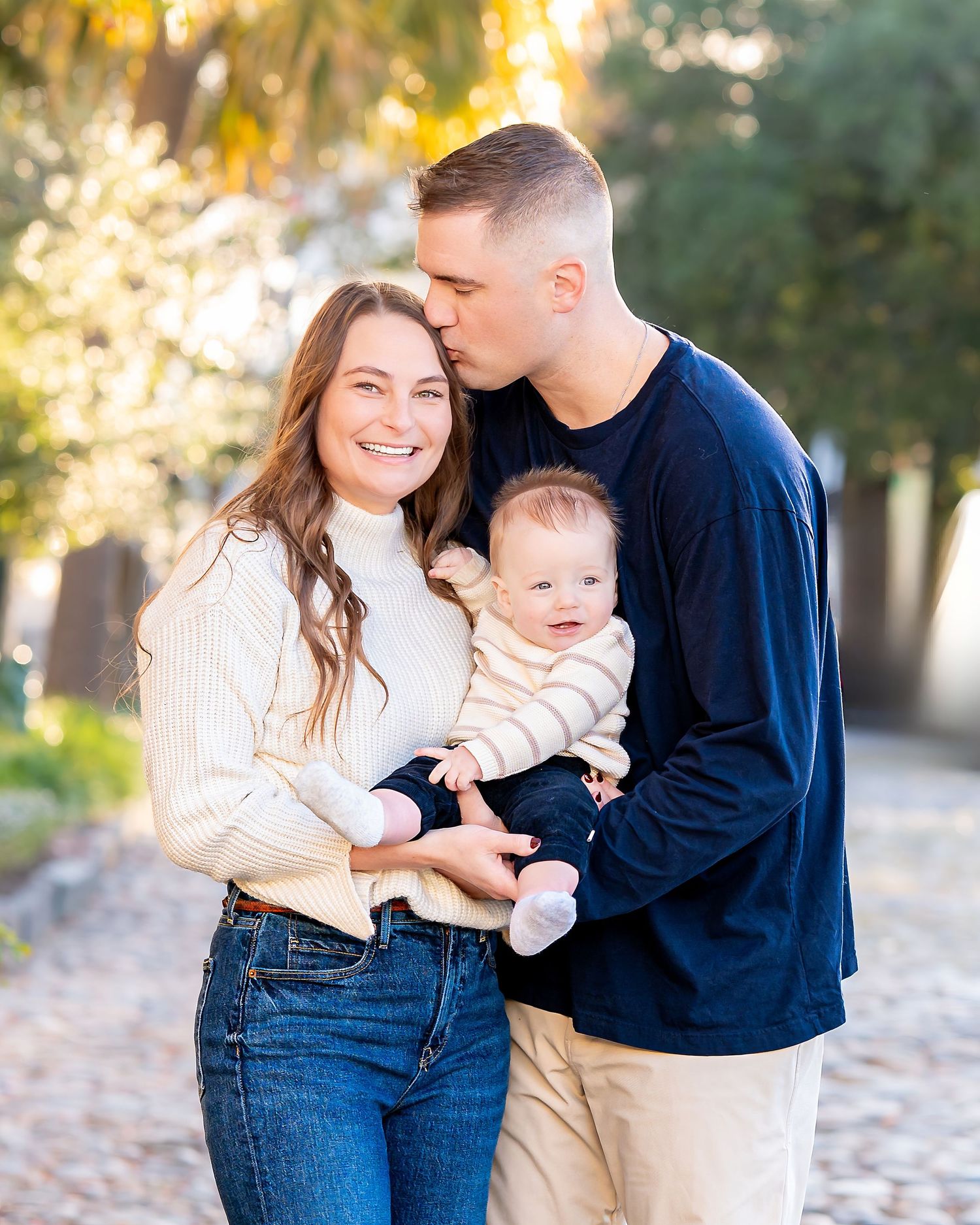 Young family with baby enjoying tender moments together in casual fall attire.