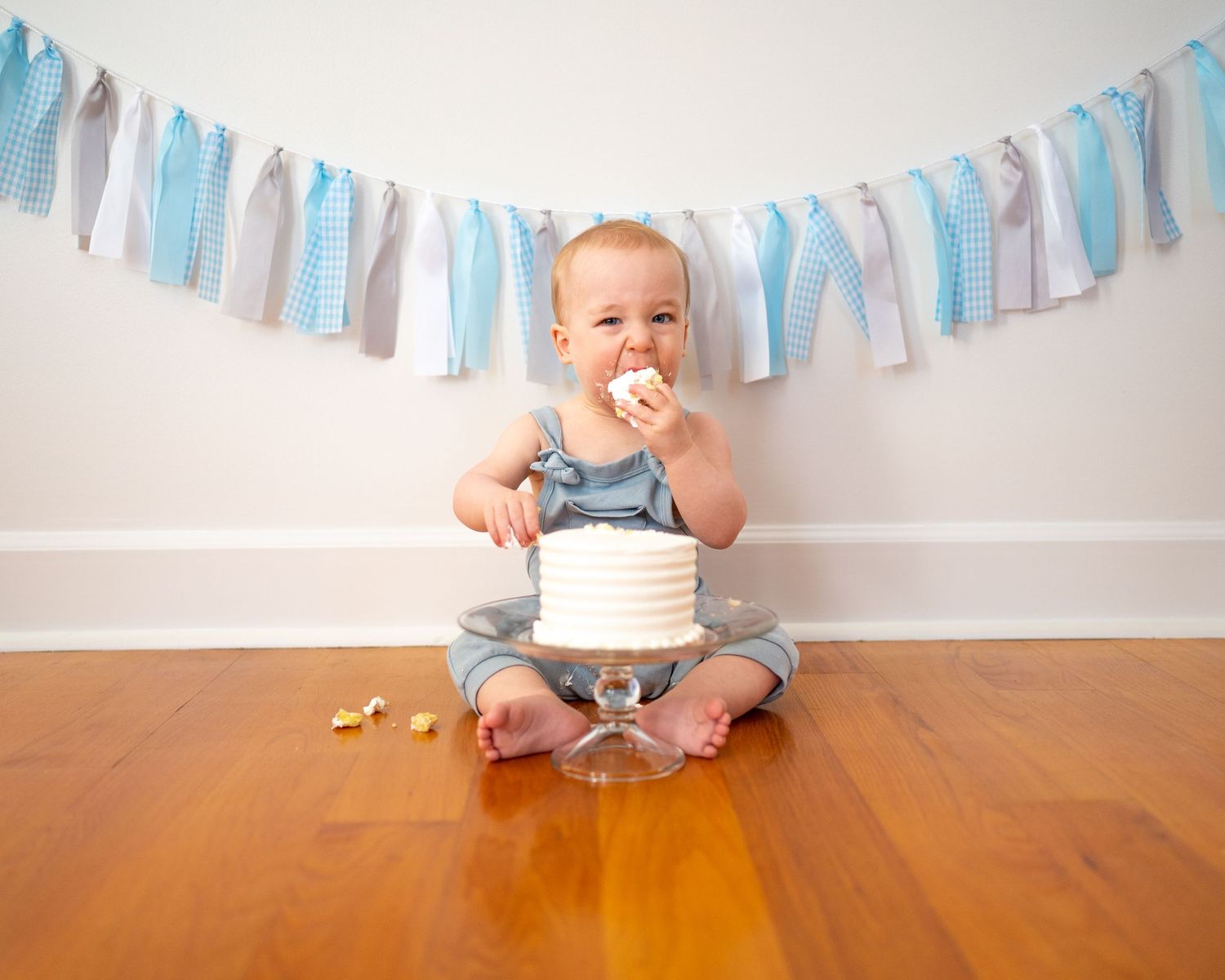 Cake smash session with a little boy eating a large chunk of cake