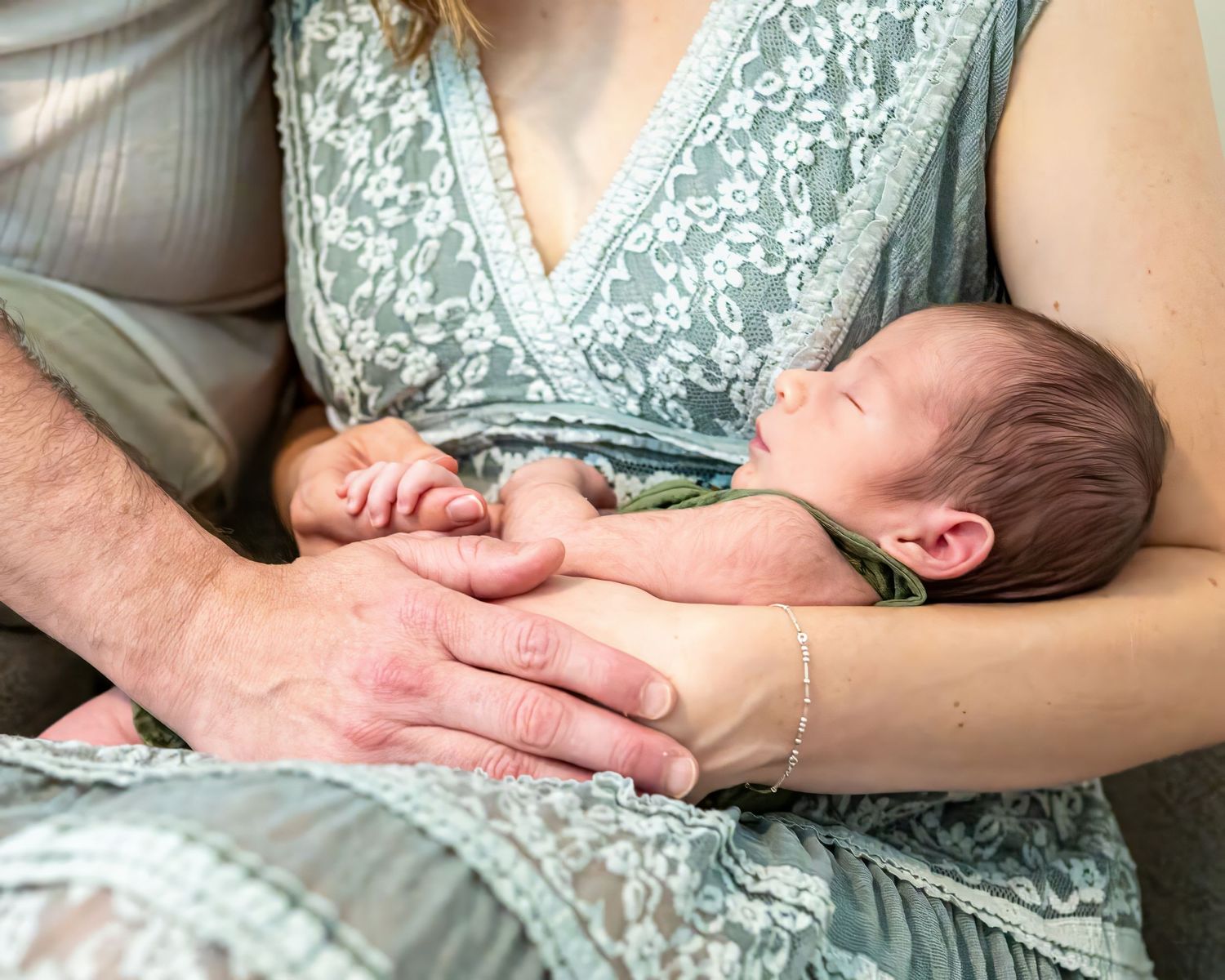 Parent and newborn baby lie together in loving skin-to-skin bonding moment on bed.