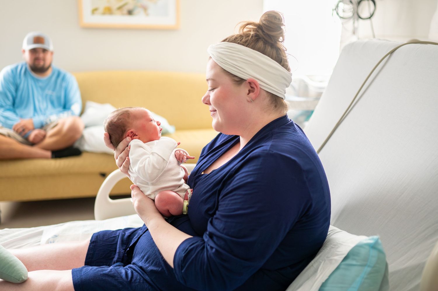 Sarah sits in her hospital bed looking lovingly at her newborn son.