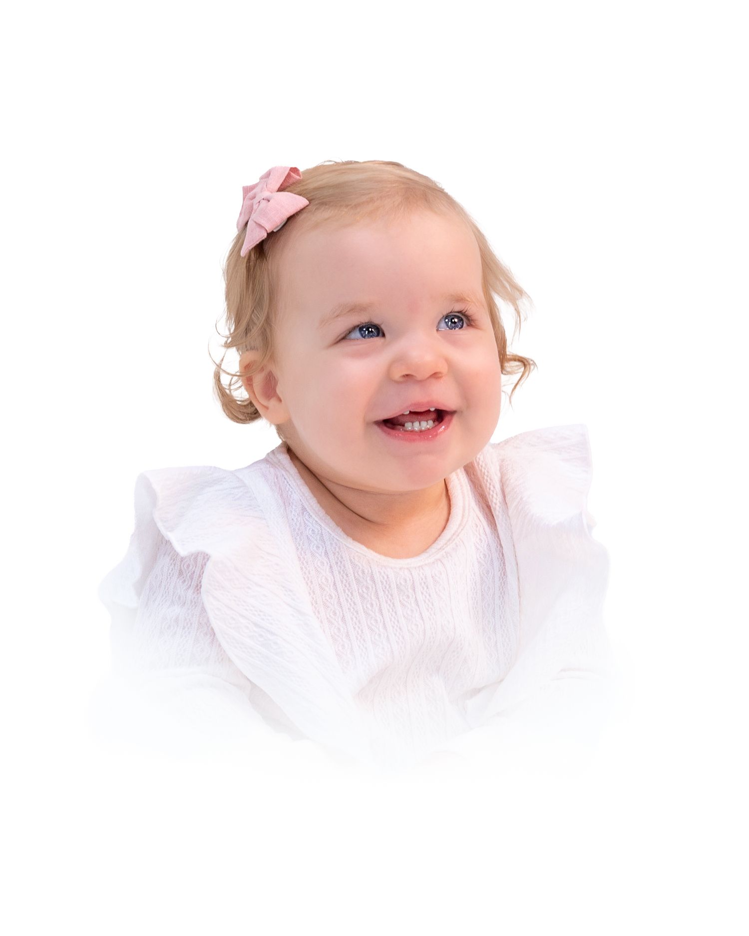 Baby in white dress with pink bow smiling joyfully against white backdrop for her heirloom portrait