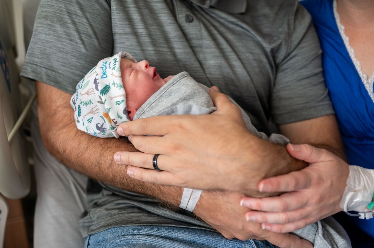Close up of a newborn boy being held in his father's arms.
