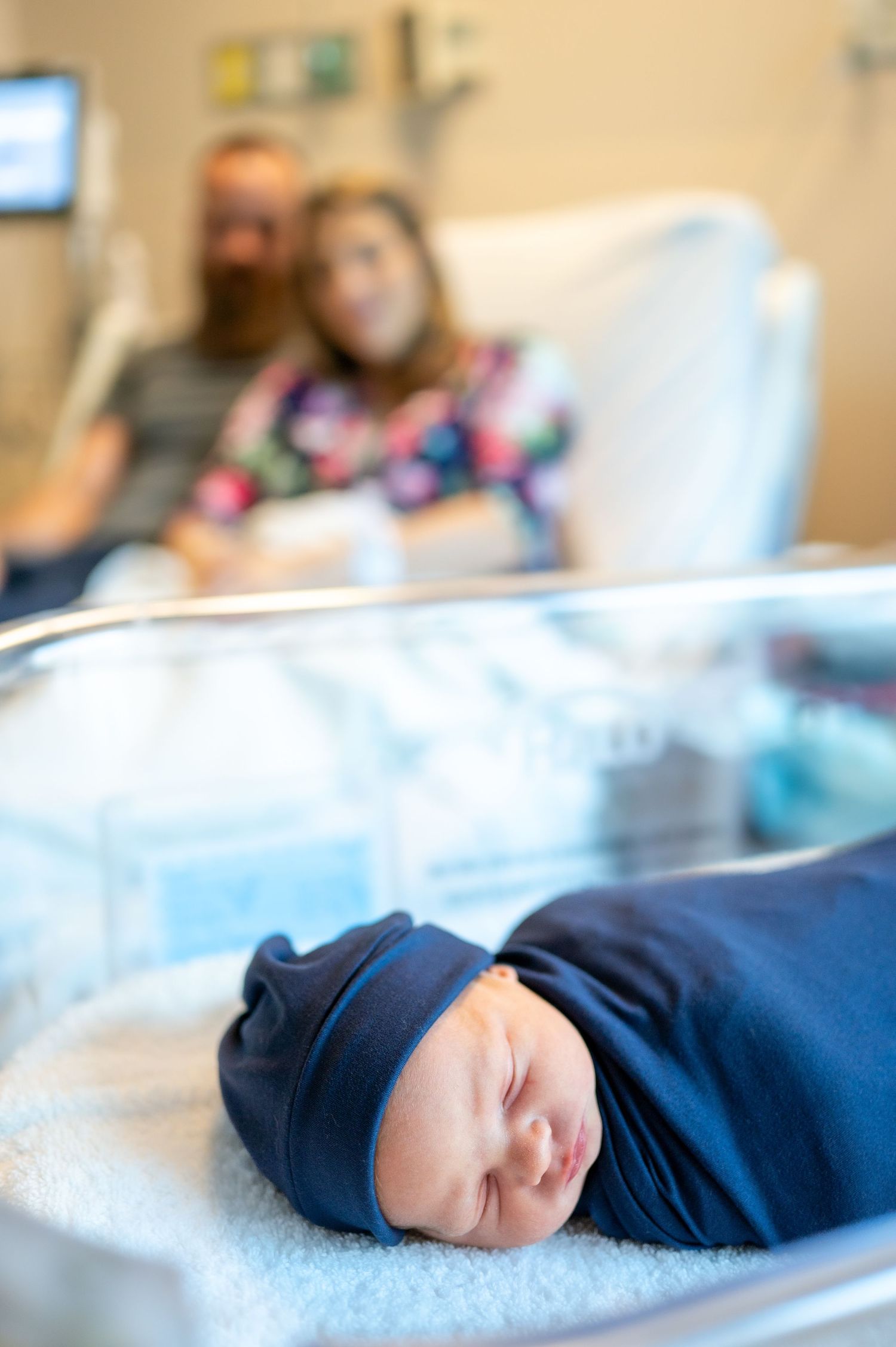 Peaceful sleeping newborn wearing navy blue outfit on soft blanket.