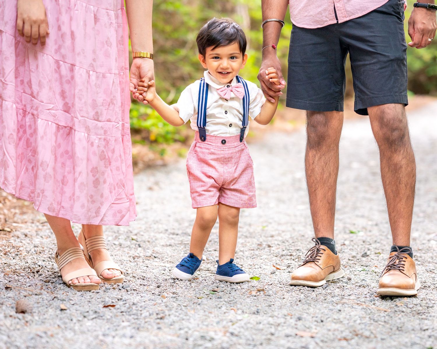 Cropped view of feet and legs of family members standing together on a gravel path.
