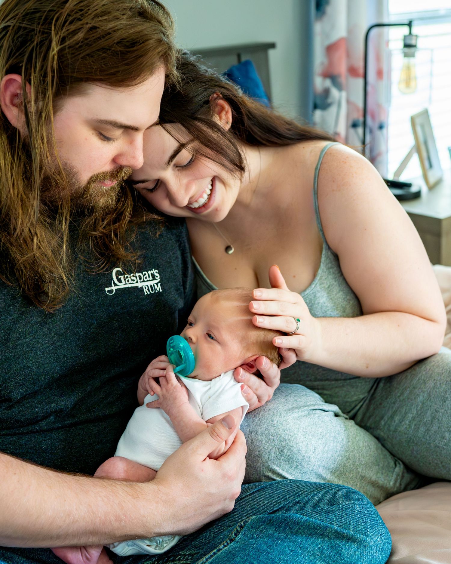 A cozy family moment on the couch with their newborn baby in a casual home setting.