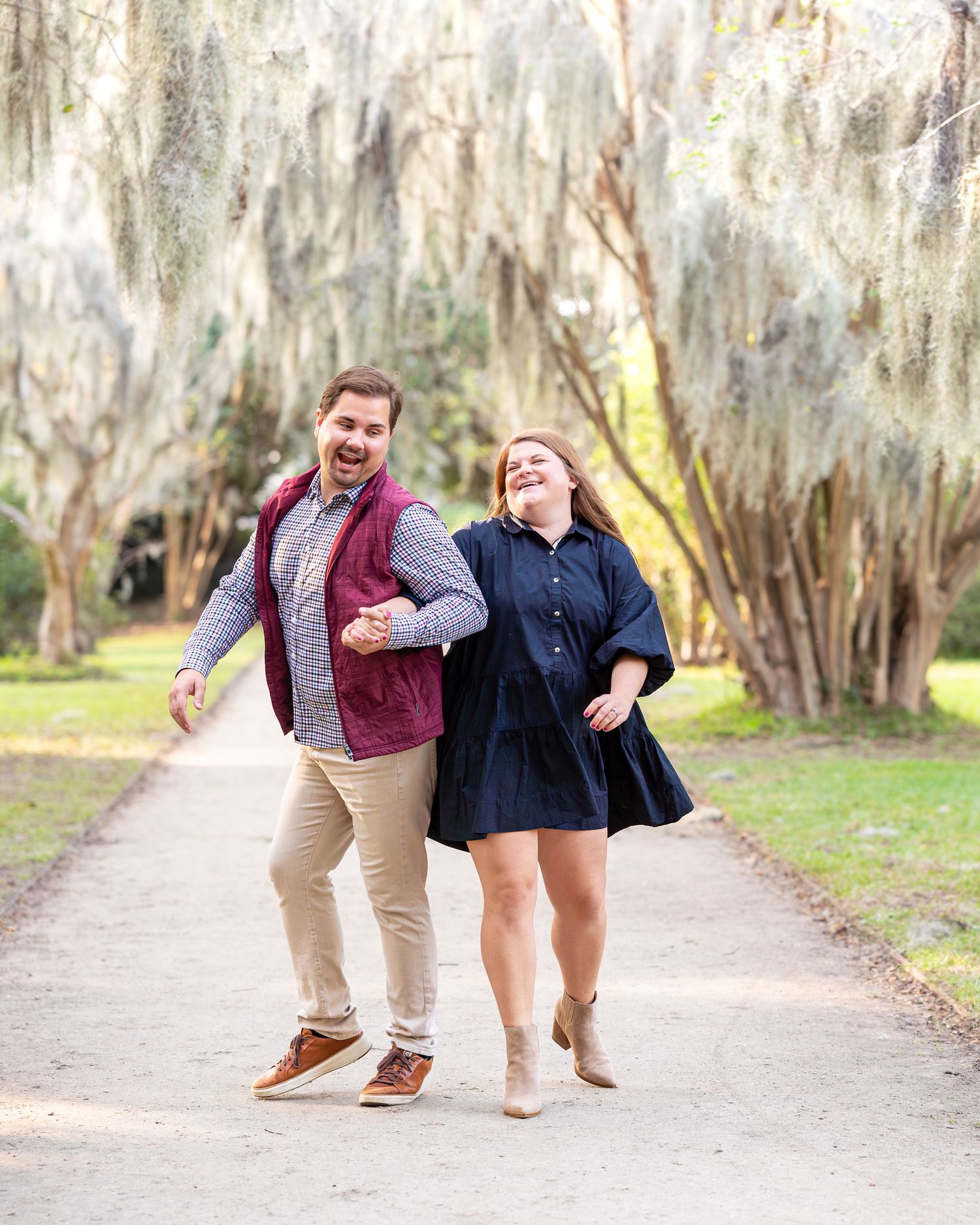 Playful couple dancing and twirling together on a scenic outdoor pathway.
