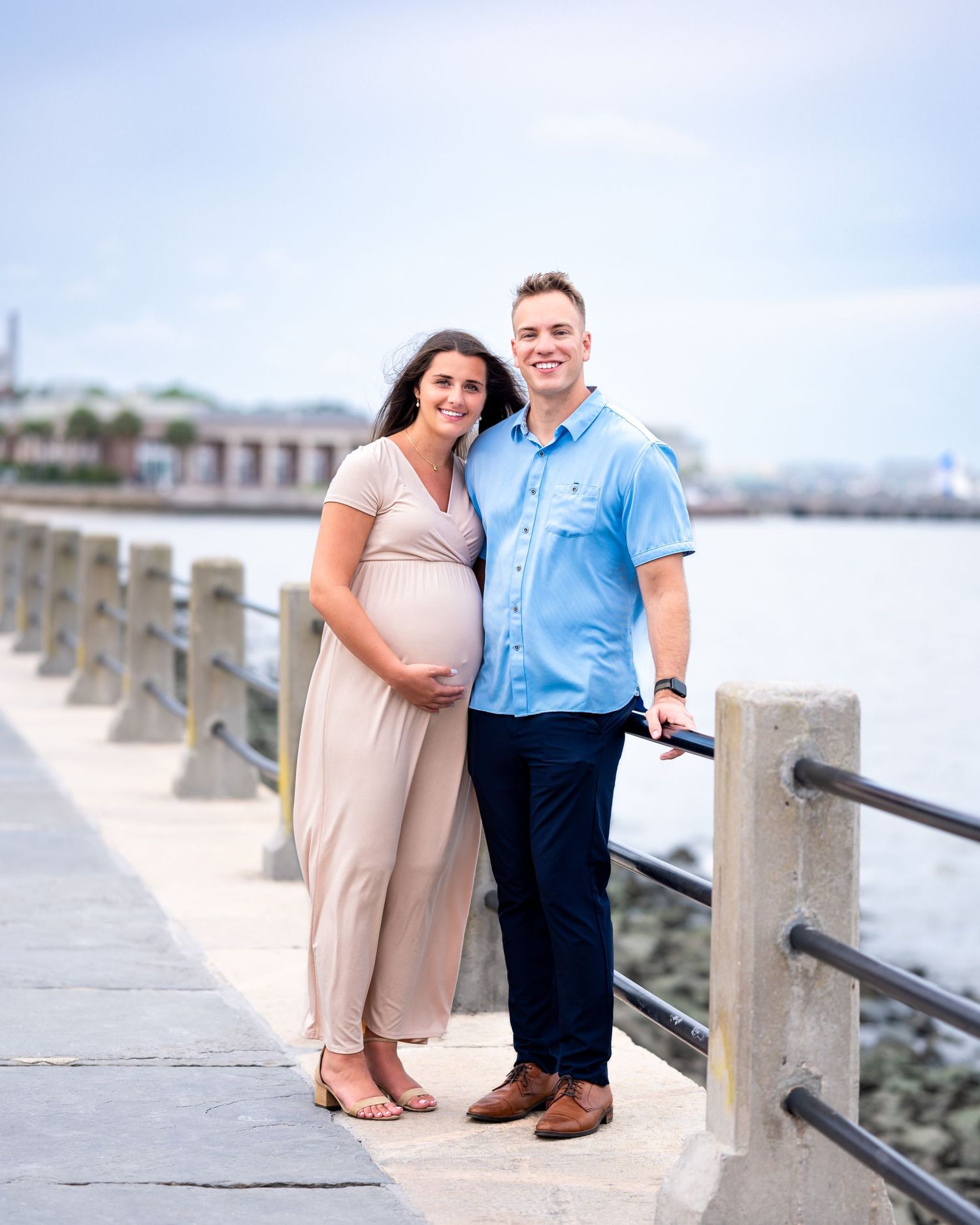 Husband and pregnant wife stand along the Charleston Battery.