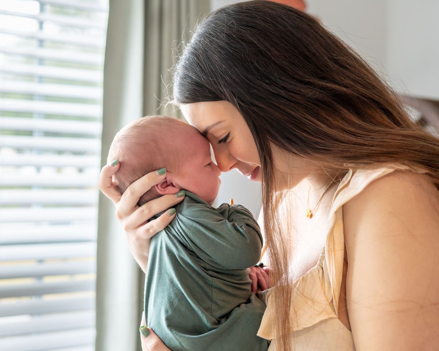 Tender moment in nursery with couple holding newborn near window.