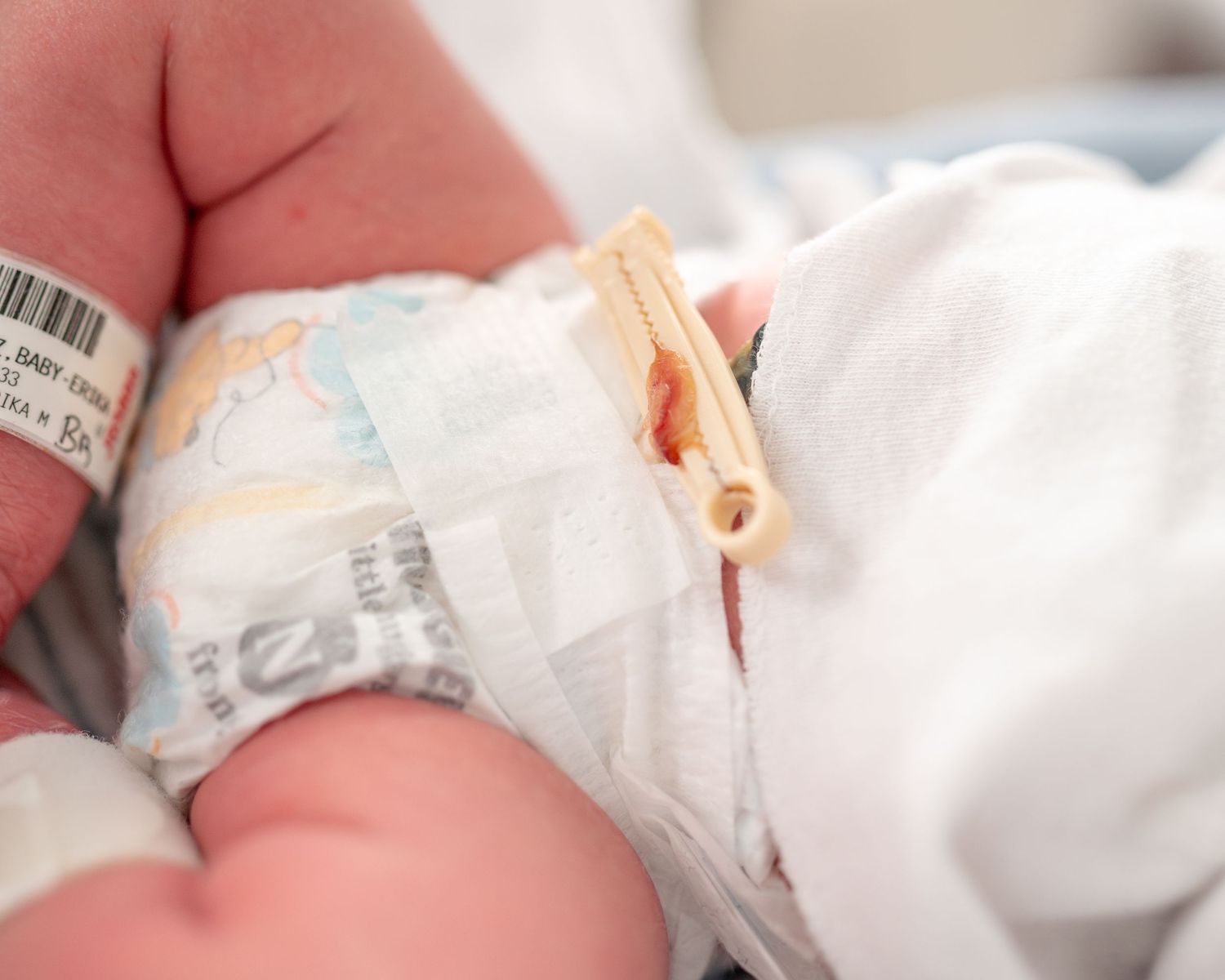 Close-up series of a newborn baby wearing a white onesie in a hospital bassinet.