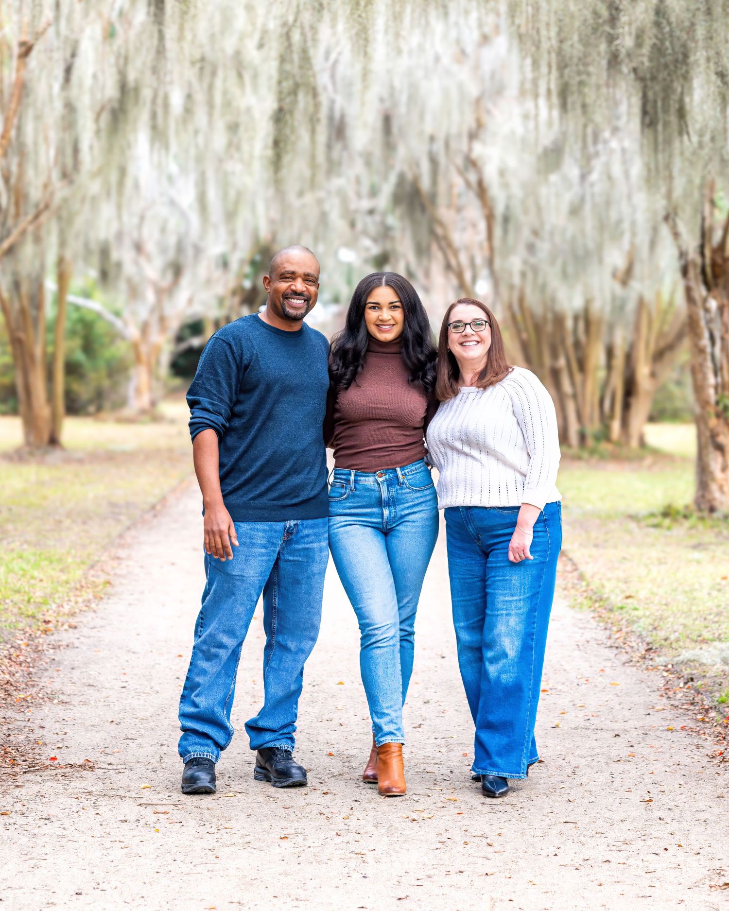 People walking together on a dirt path with Spanish moss hanging from trees in the background.