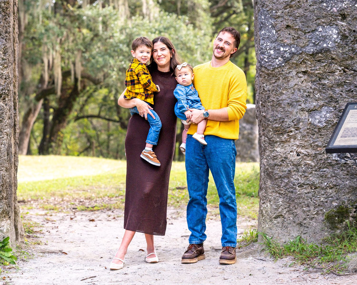 Edited photo: A family stands next to a rocky wall in wearing coordinating fall colors in yellows and browns