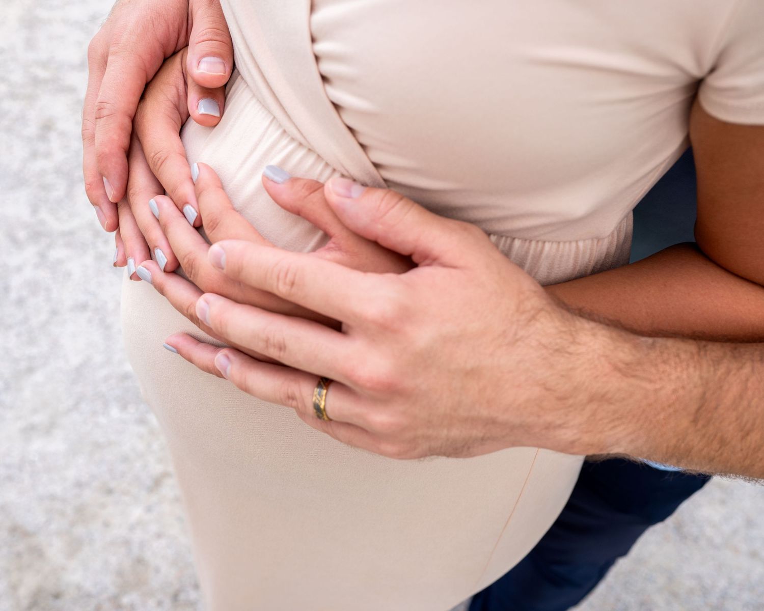 Close up of baby bump with mom and dad's hands wrapped over it