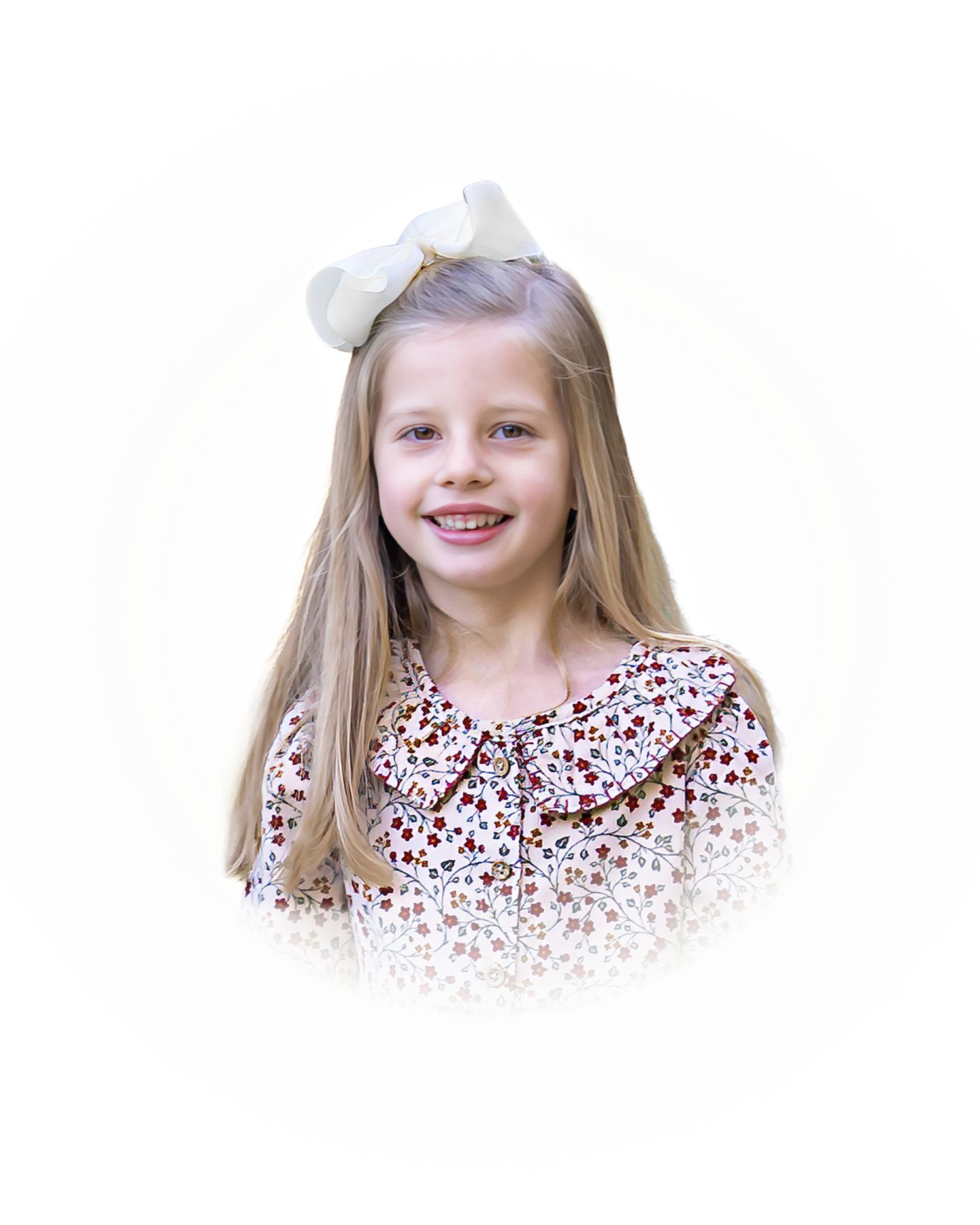 Young child wearing a red and white patterned dress with a white bow smiling at the camera against white background.