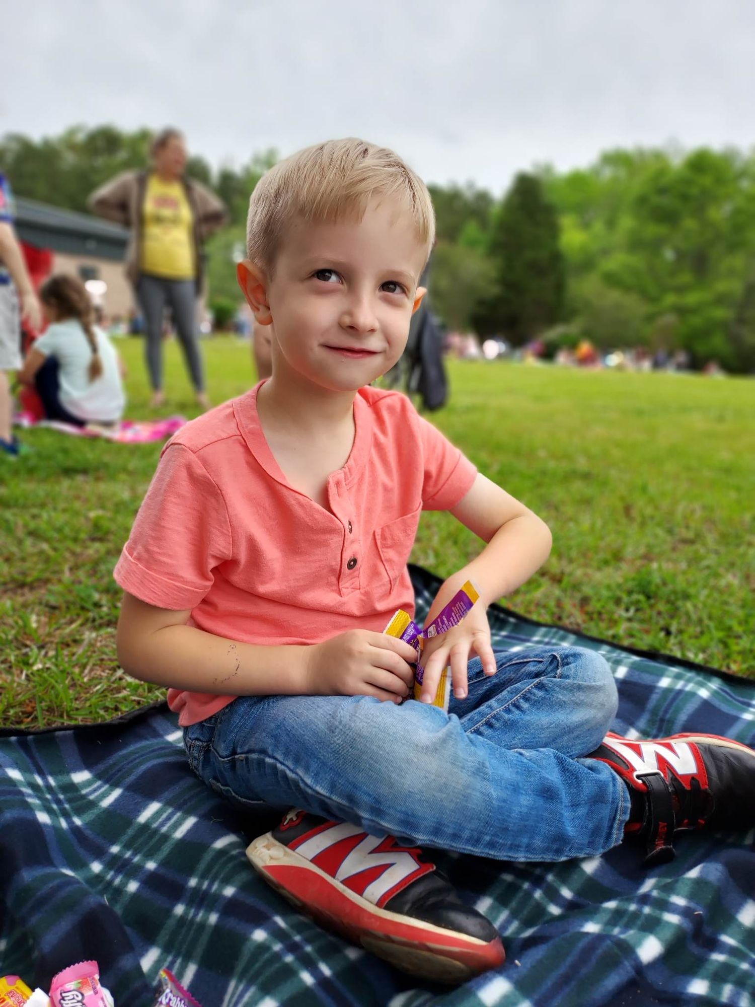 Four year old Evan sits on a blanket eating candy at a school event