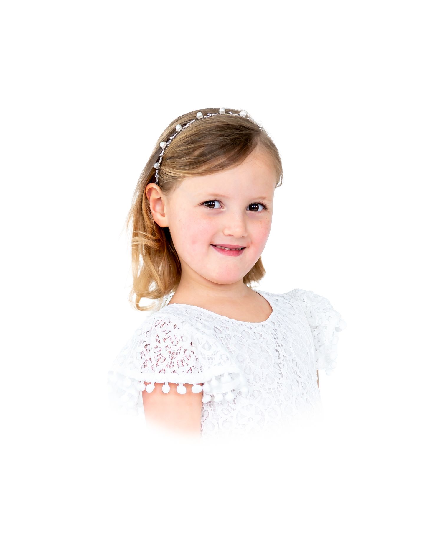 Young girl in white lace dress with pearl headband, smiling portrait photo.