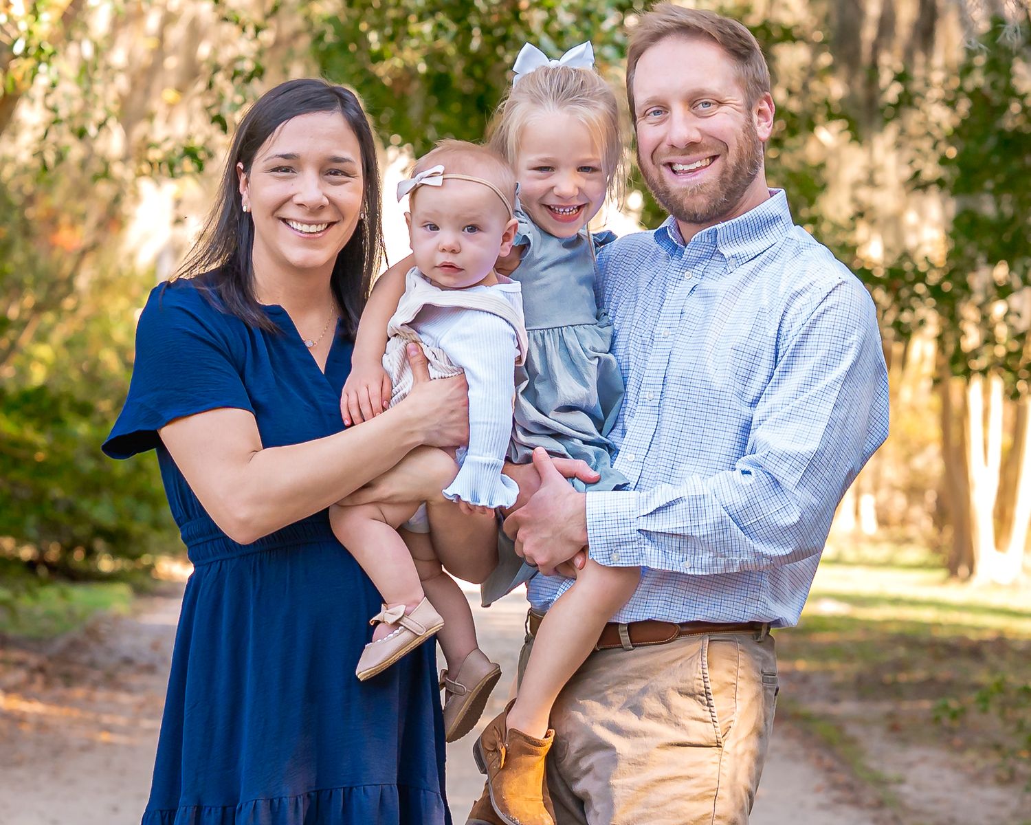 Group portrait in coordinated navy and light blue outfits standing on an outdoor path.