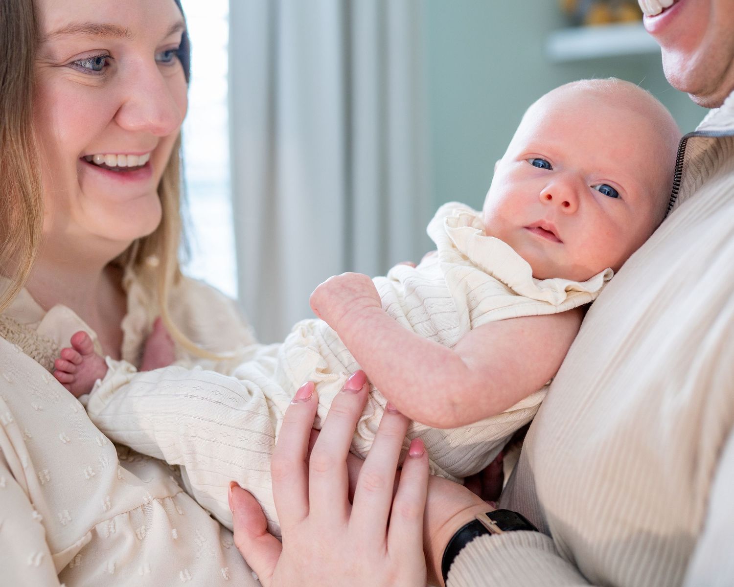 A newborn baby being held and cuddled by her parents during a lifestyle newborn session.