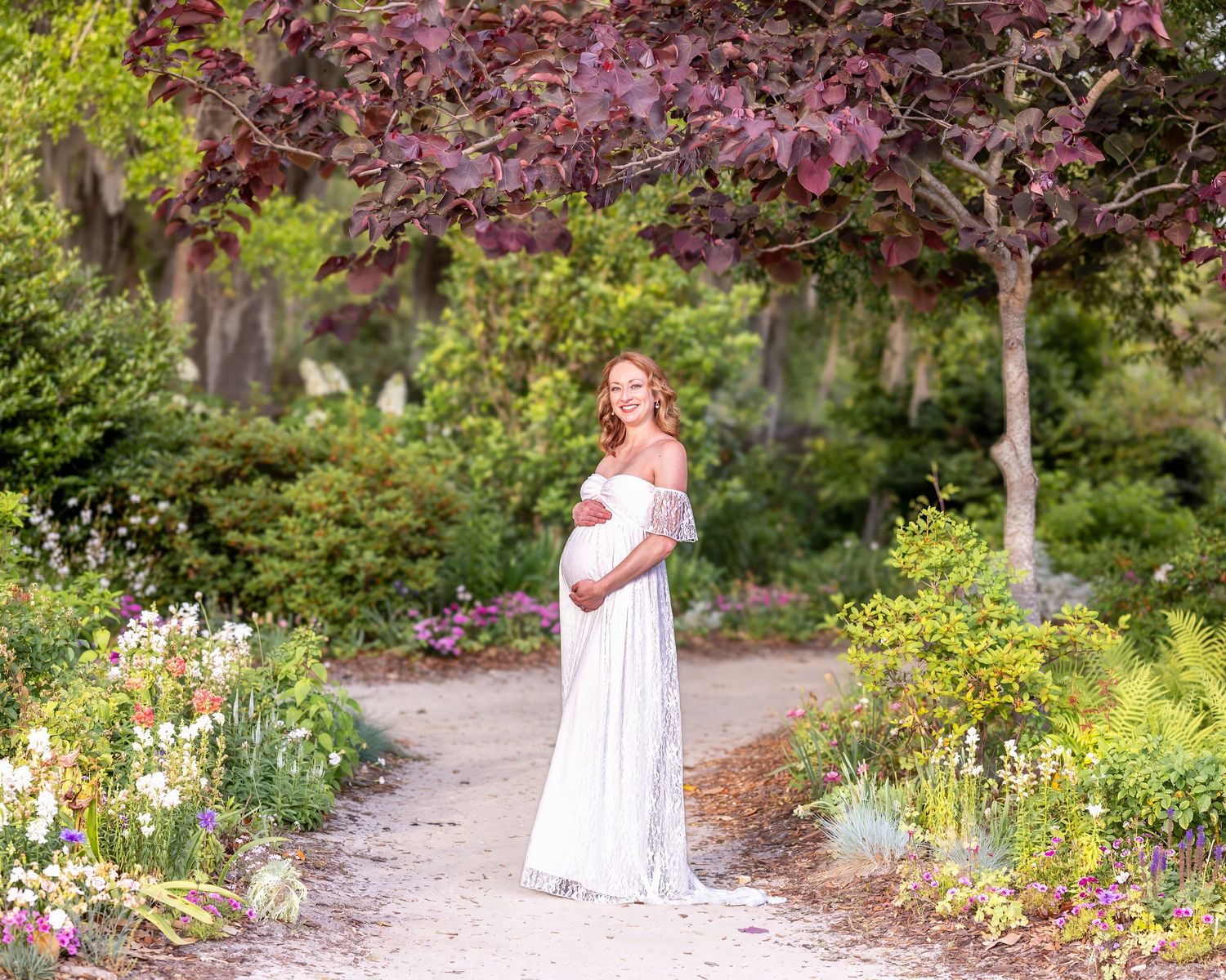 A pregnant woman poses in a luscious garden at Hampton Park during her maternity session.