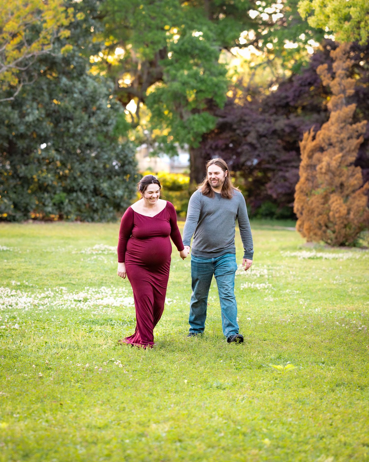 A couple takes a romantic stroll together through a park with autumn foliage in the background.