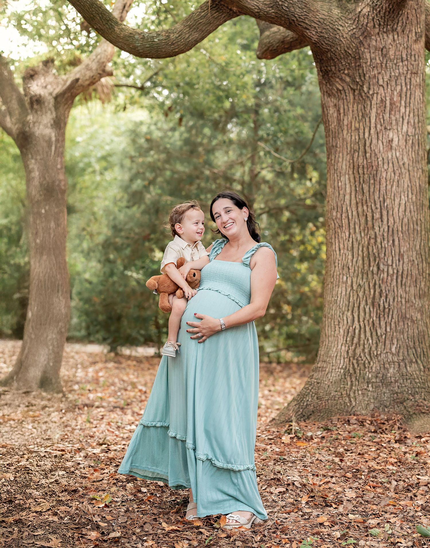 Edited photo of a maternity session where a mom wearing a blue dress holds her toddler son who is looking at her adoringly.