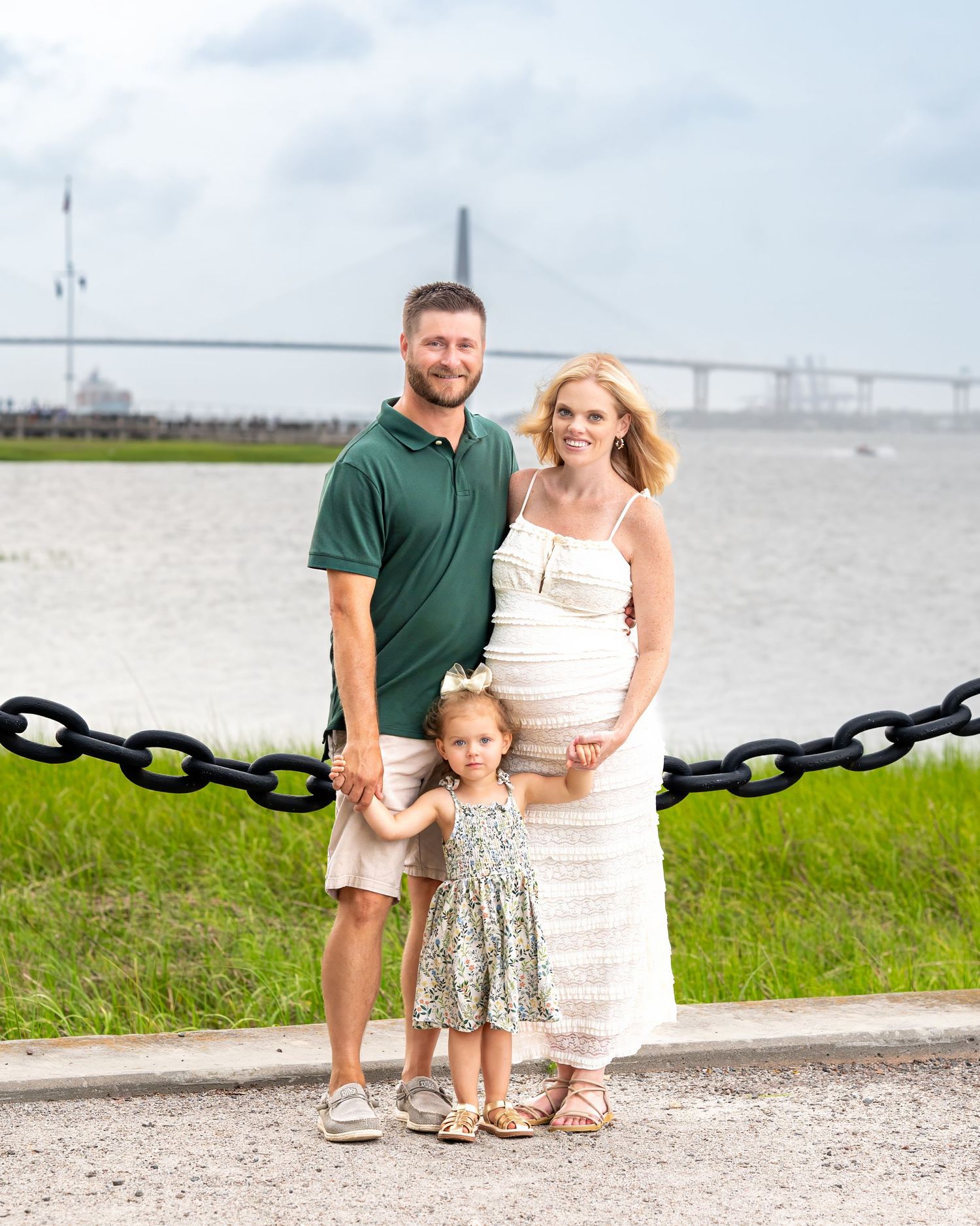 A family poses together with the Ravenel Bridge in the background during their family maternity session.