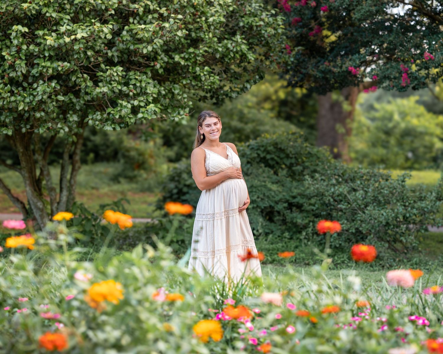 A dreamy maternity portrait in a garden filled with vibrant orange and yellow flowers.