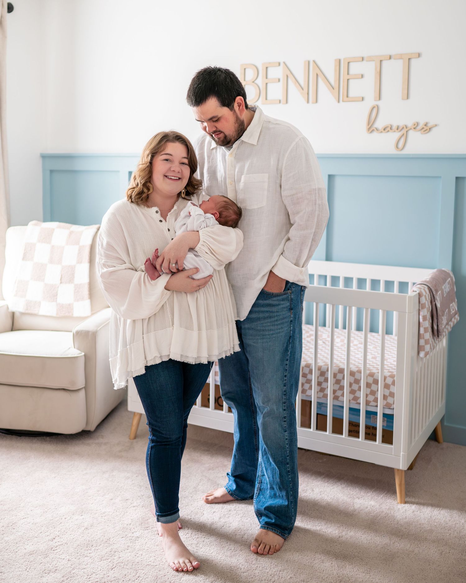Ally and Charles stand in their nursery holding their newborn son during their lifestyle newborn session
