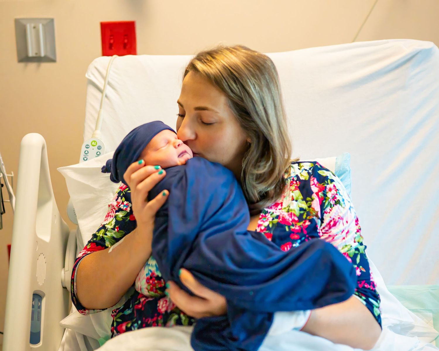 Tender moment shared with newborn baby wrapped in blue at the hospital.