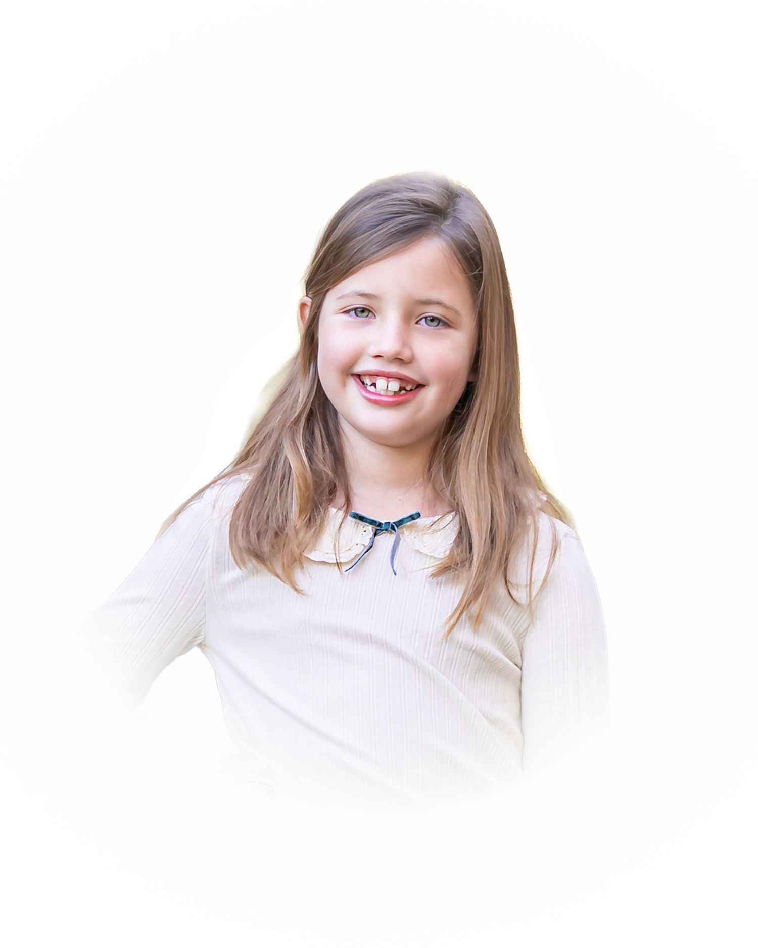 Child in white dress with blonde hair smiling warmly against pure white backdrop.