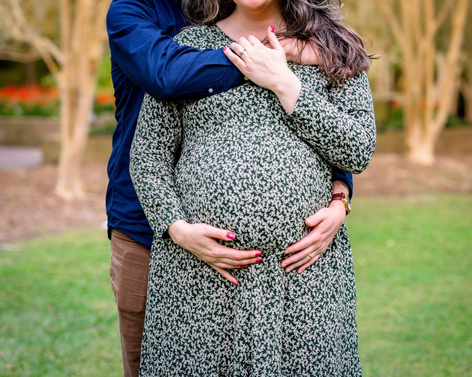 Close up of Erin's pregnant belly as she and her husband embrace it