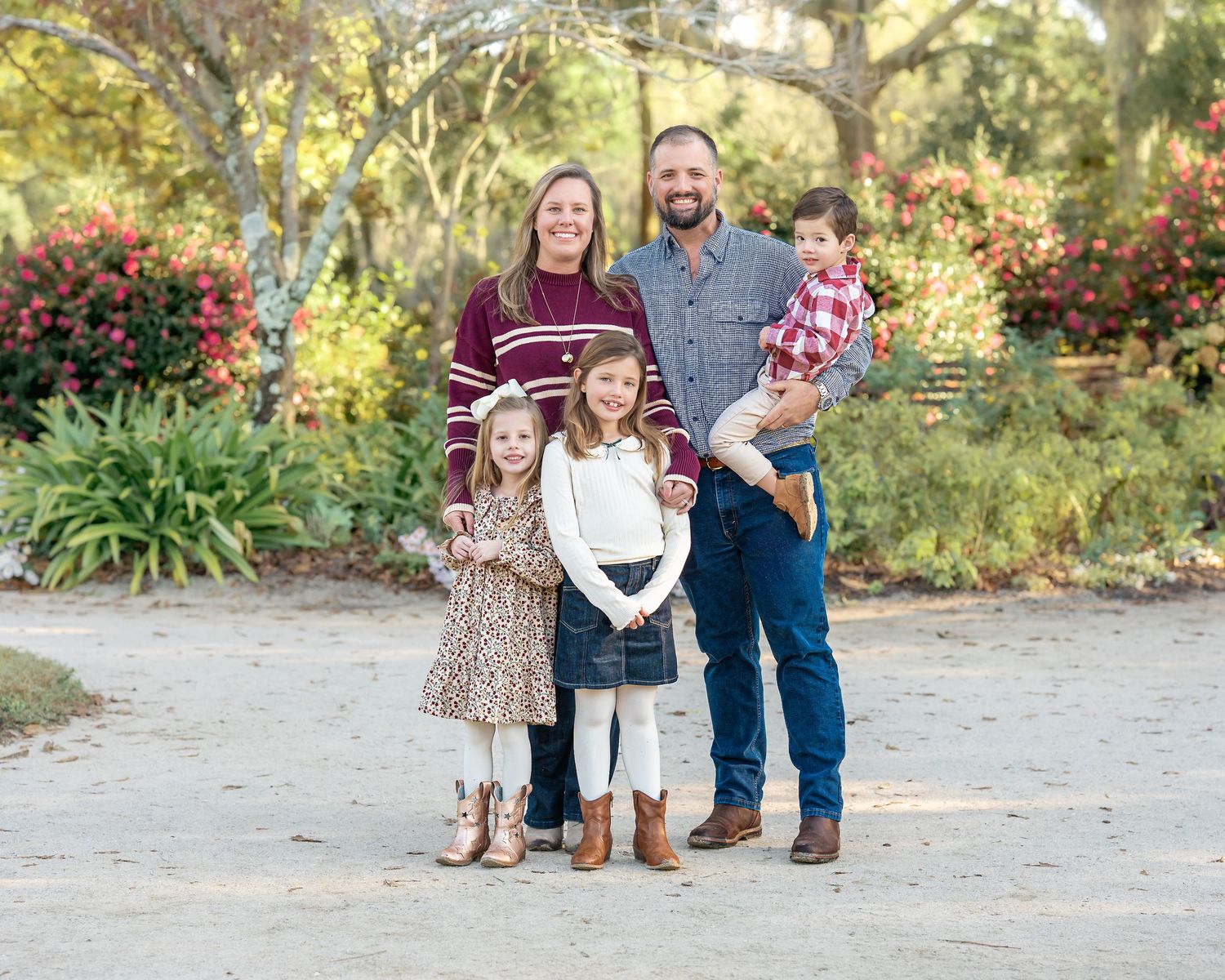 Family portrait session in a natural outdoor setting with lush greenery and sunlit background.