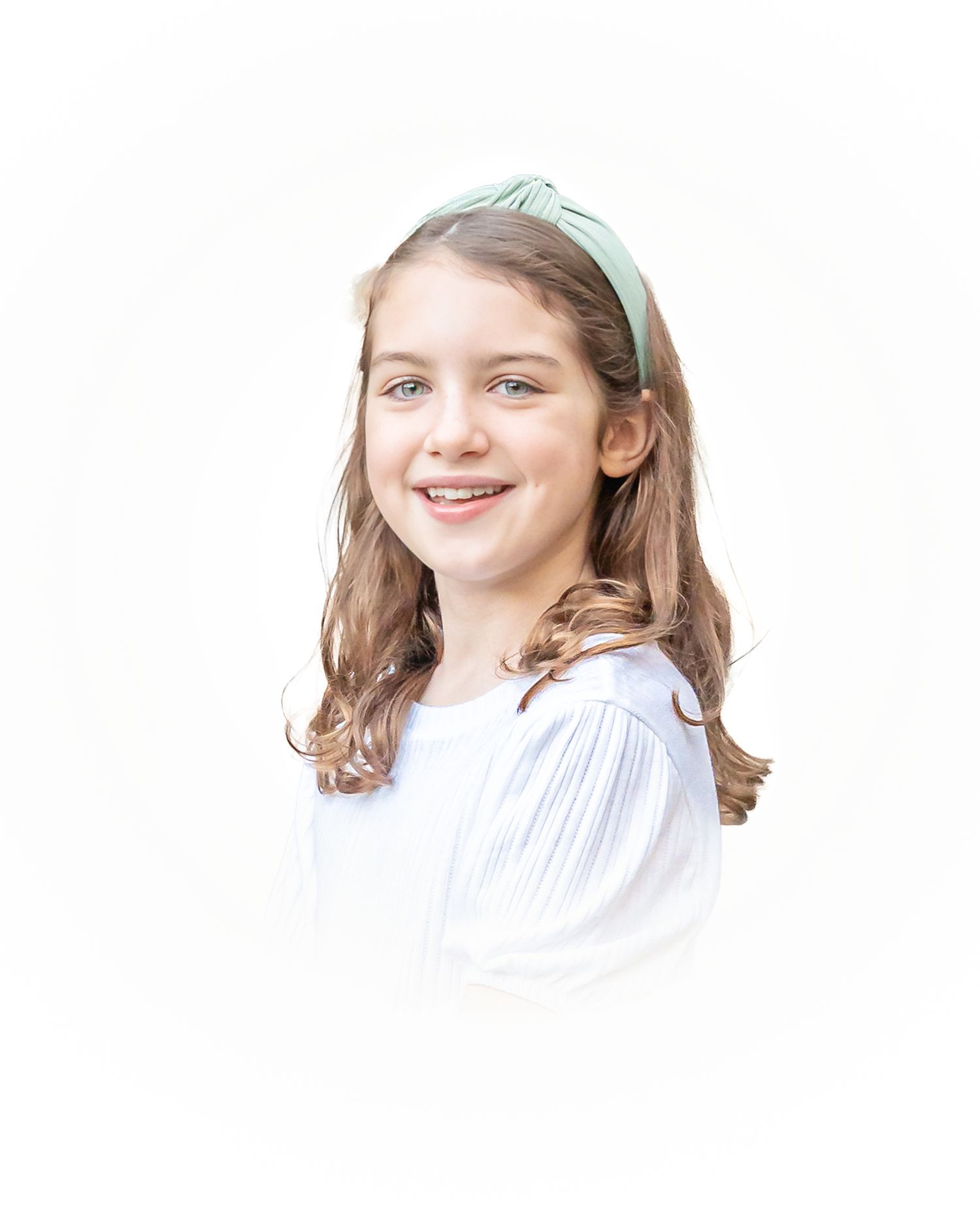 Child in white dress with light blue bow accessory smiling against white background.