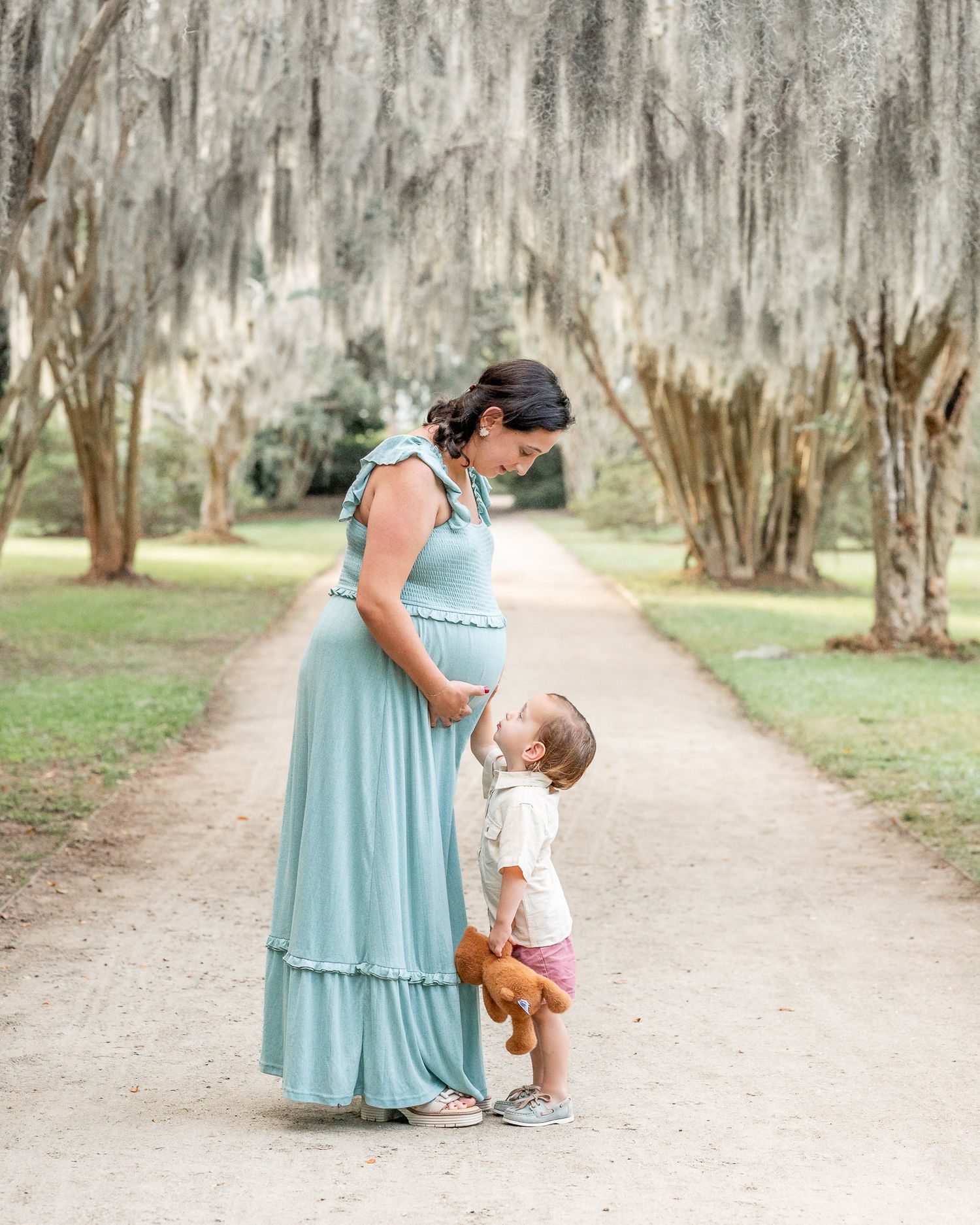 A tender moment shared between parent and child in matching blue and white outfits on a tree-lined path.