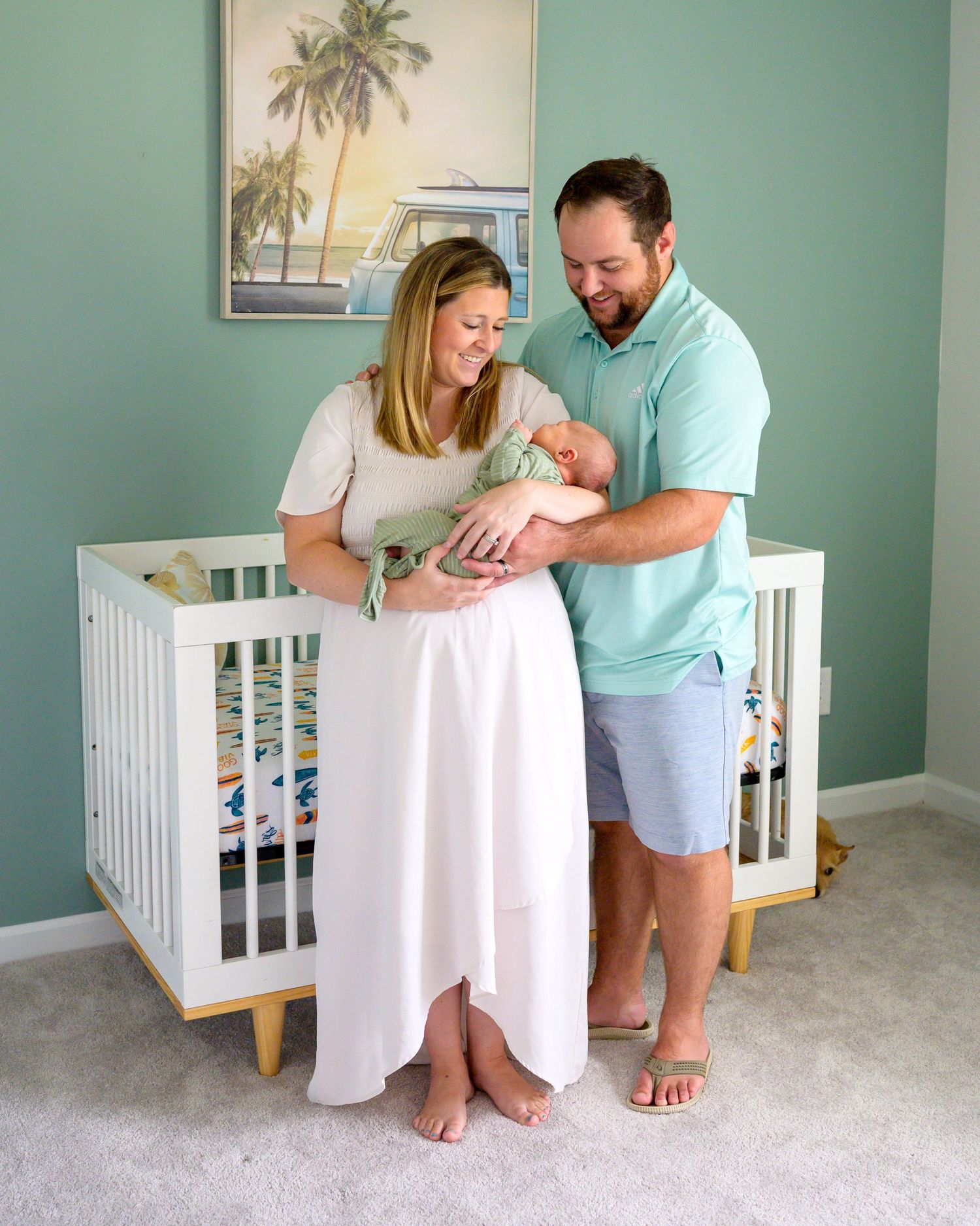 Amanda and her husband stand in their nursery holding their newborn son.
