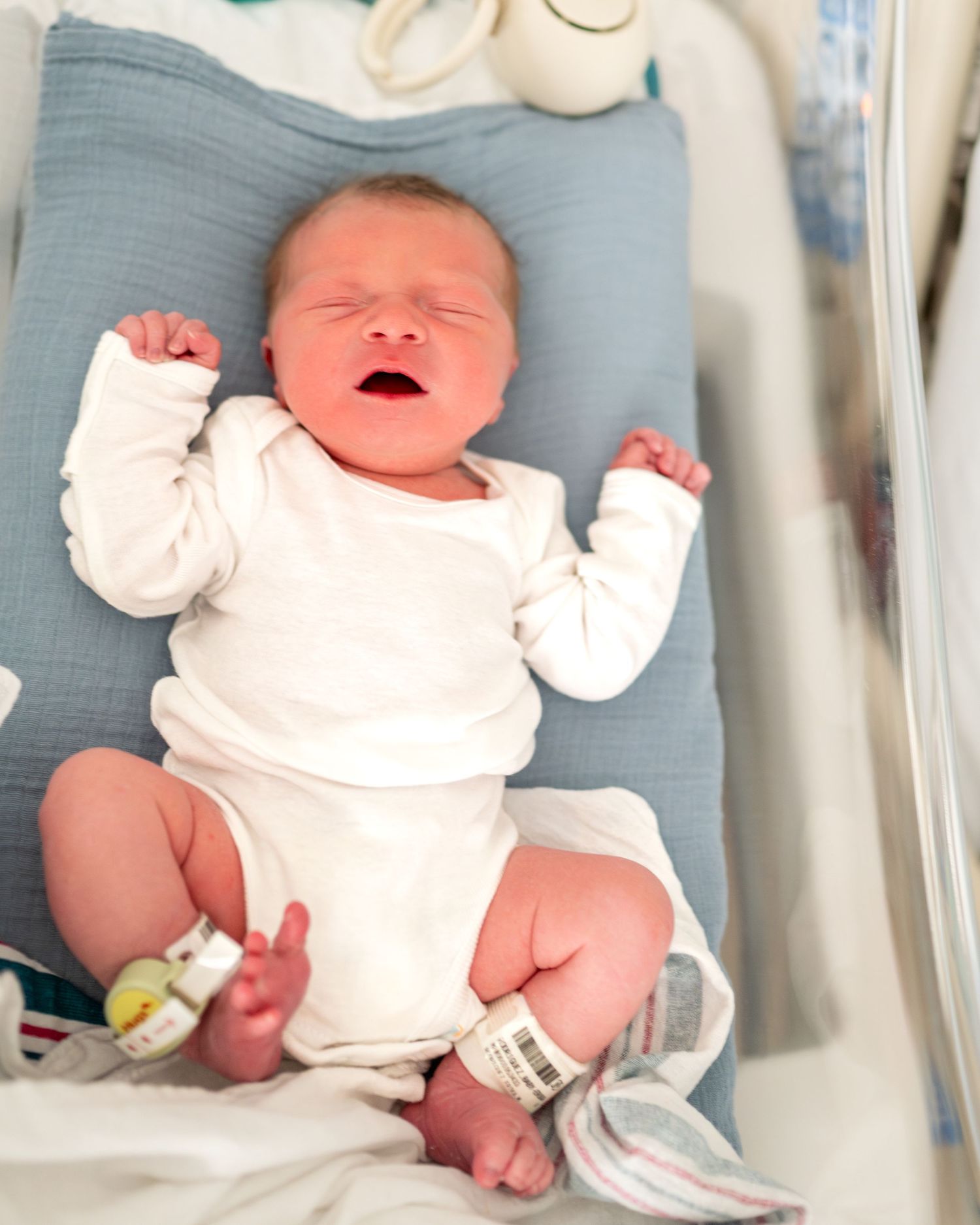 Sequential images of a newborn baby resting in a hospital bassinet with medical monitoring devices.