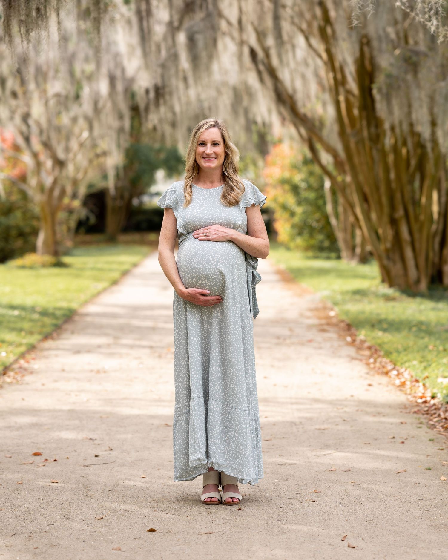 Lauren stands along the path at Hampton park as she cradles her pregnant bump during her Family Maternity Session.