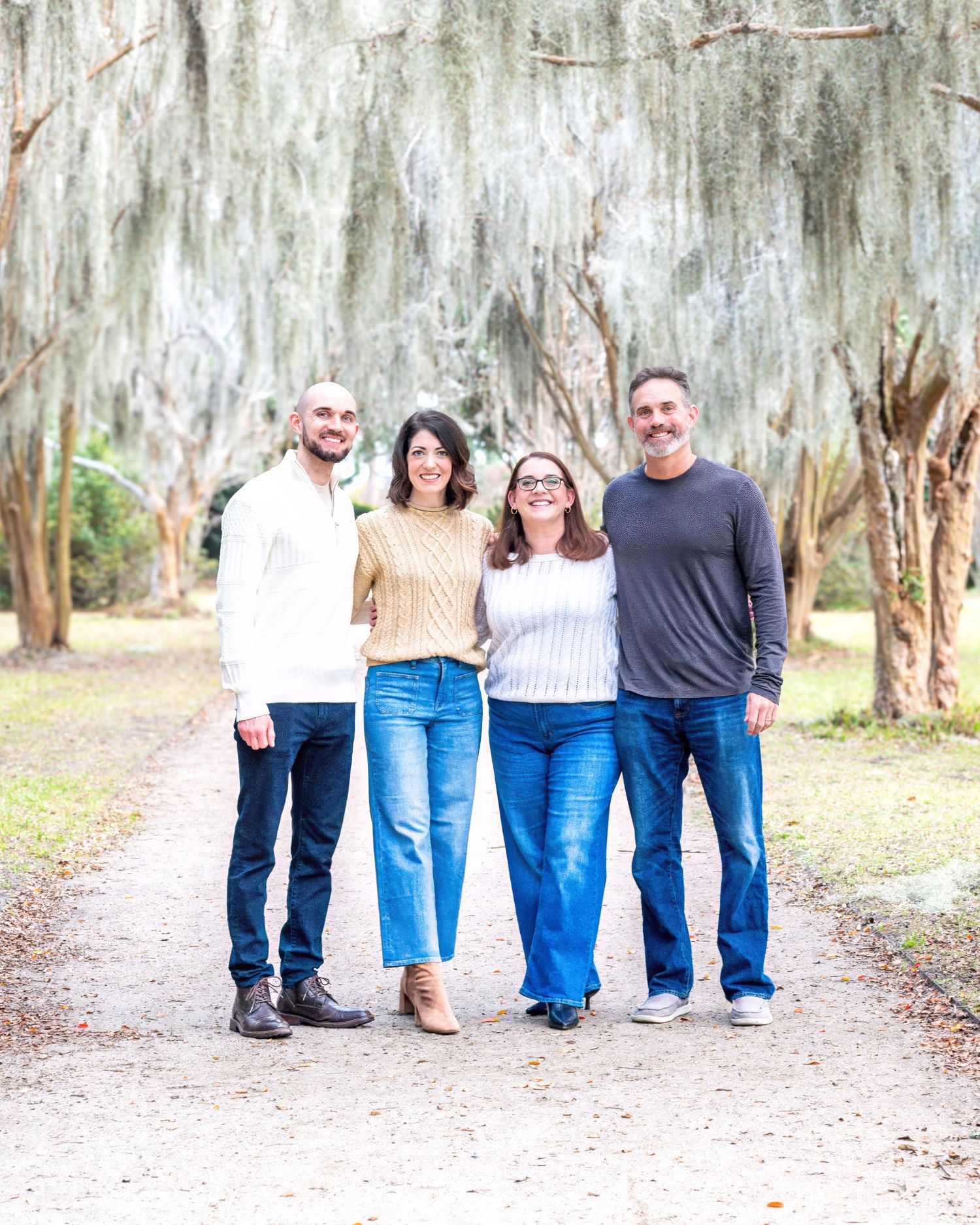 Group portrait showing legs and casual attire against a backdrop of Spanish moss covered trees.