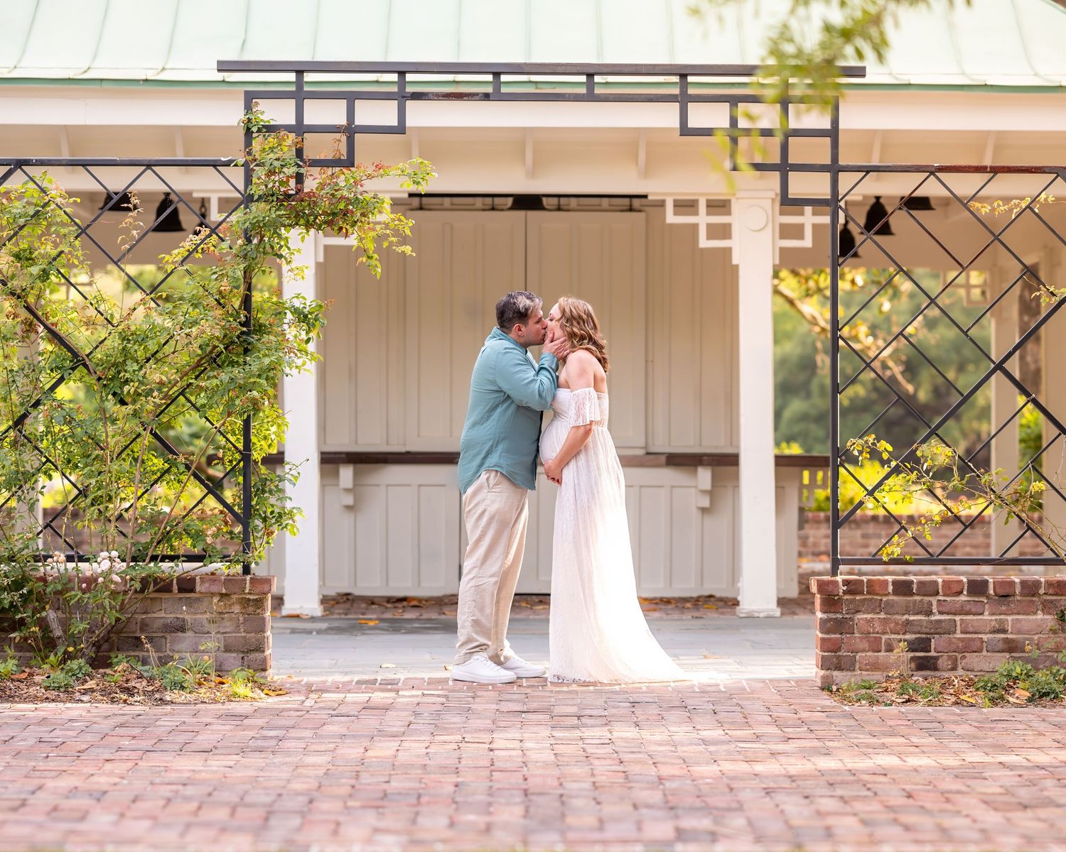 A romantic moment captured under a garden pergola with brick pavers and climbing vines.