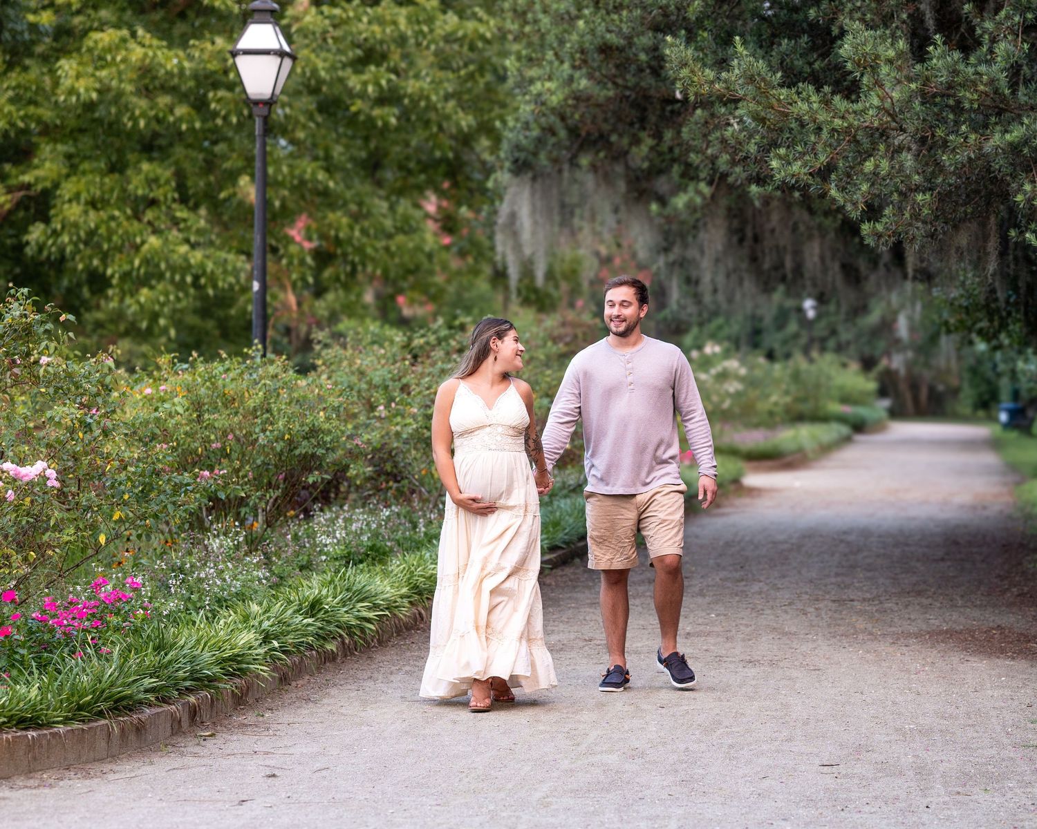 Lola and her husband walk hand in hand at Hampton Park during their maternity session