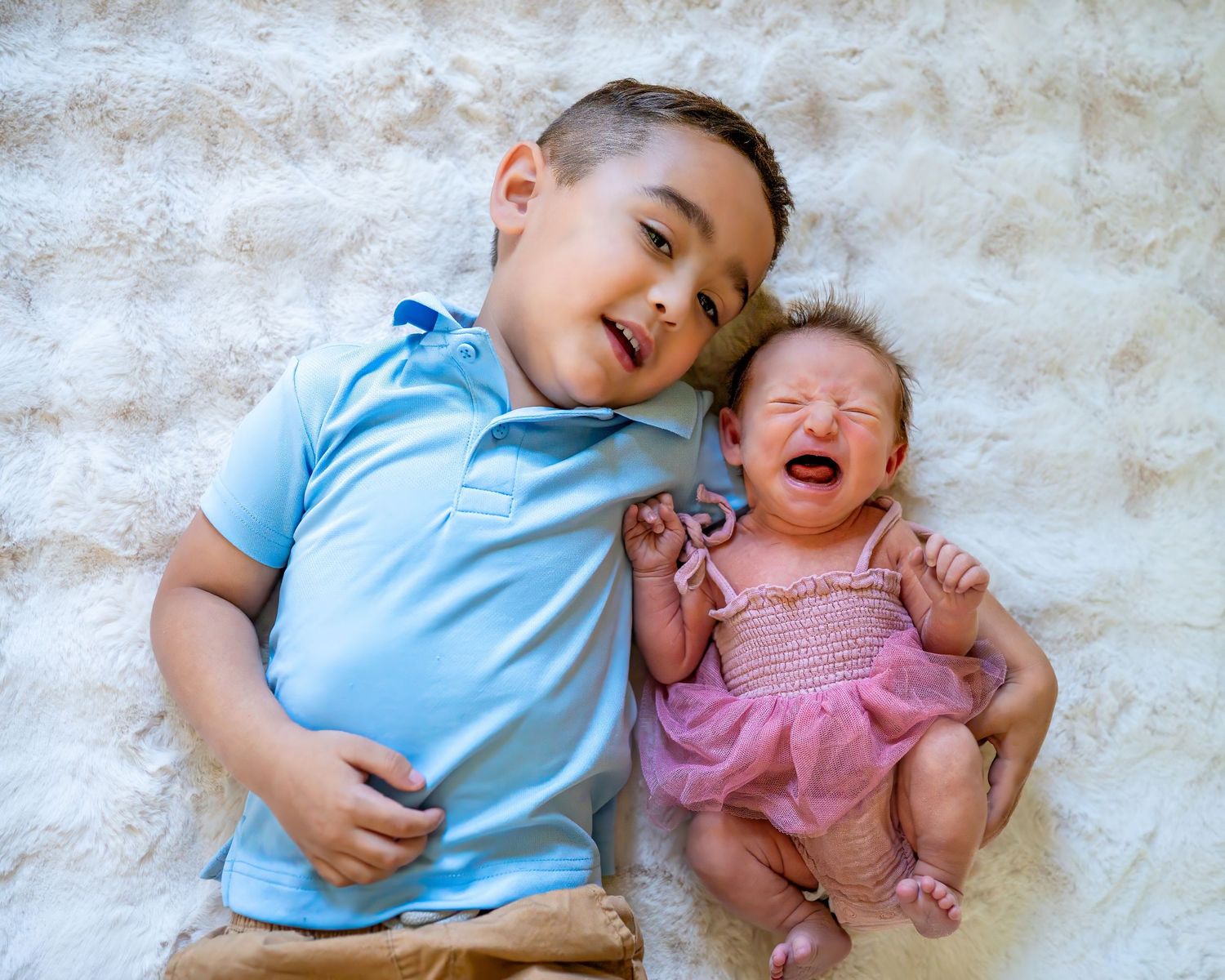 Sweet sibling interaction on textured white background.
